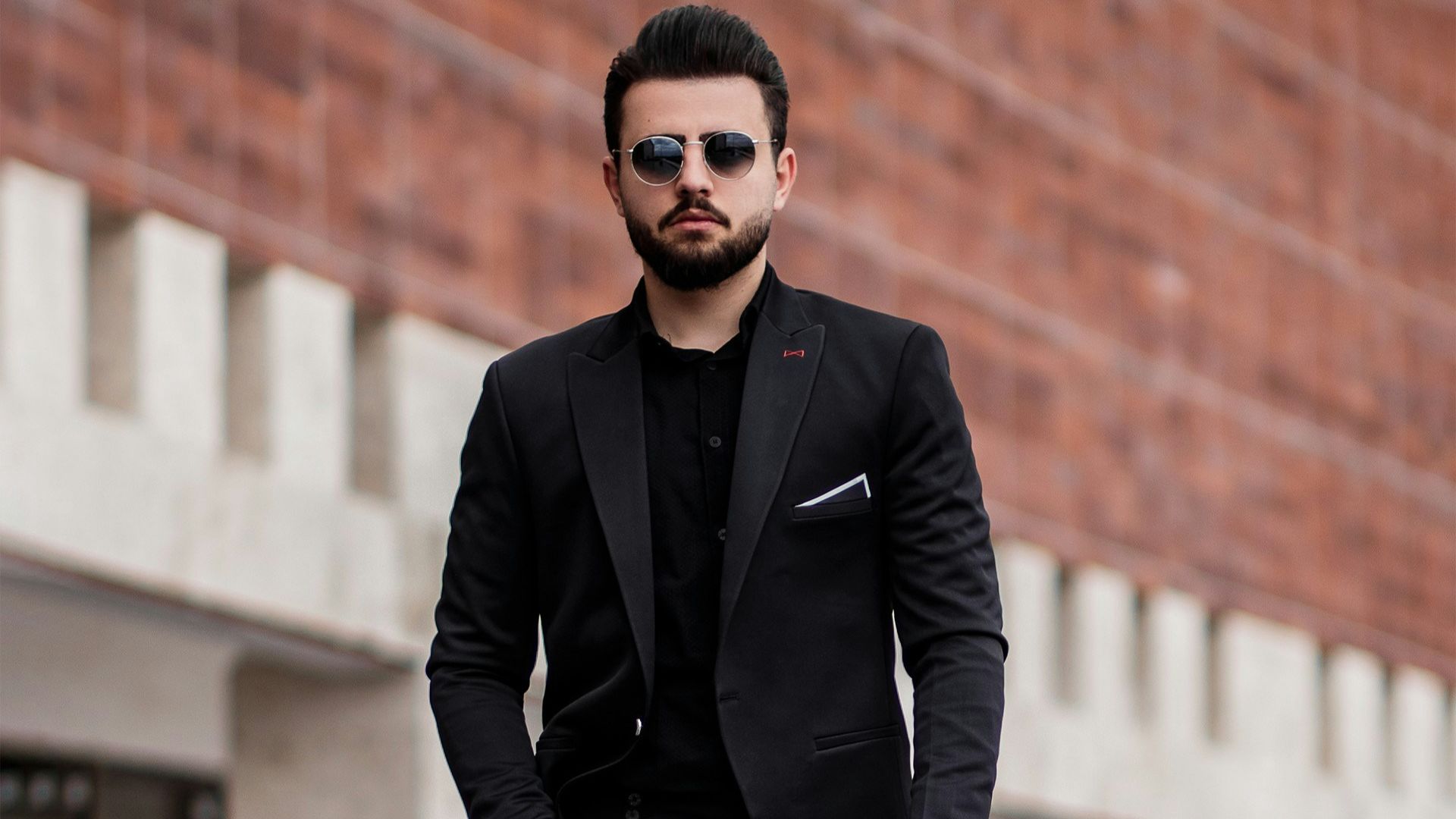 man in black suit jacket and black pants standing on gray concrete floor during daytime