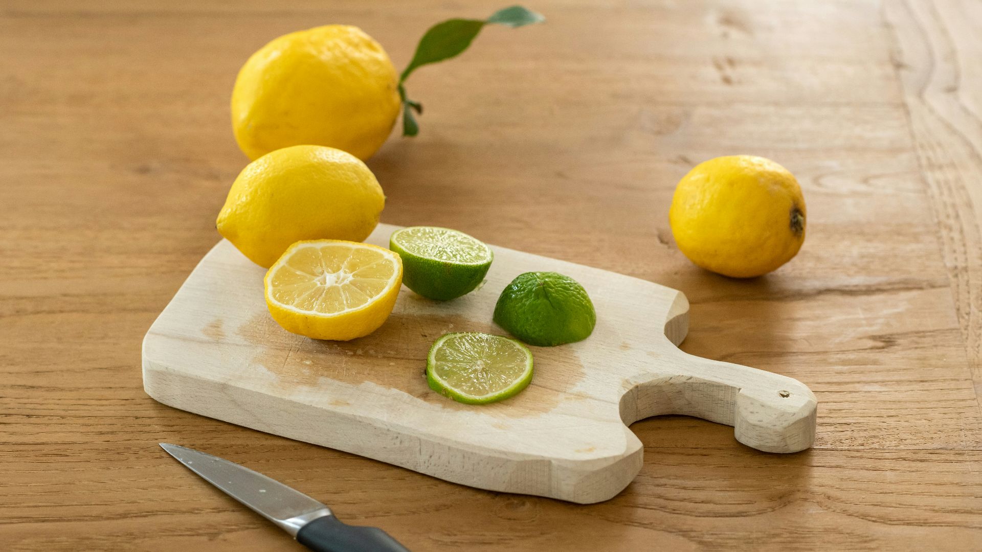 sliced lemon beside knife on brown wooden chopping board