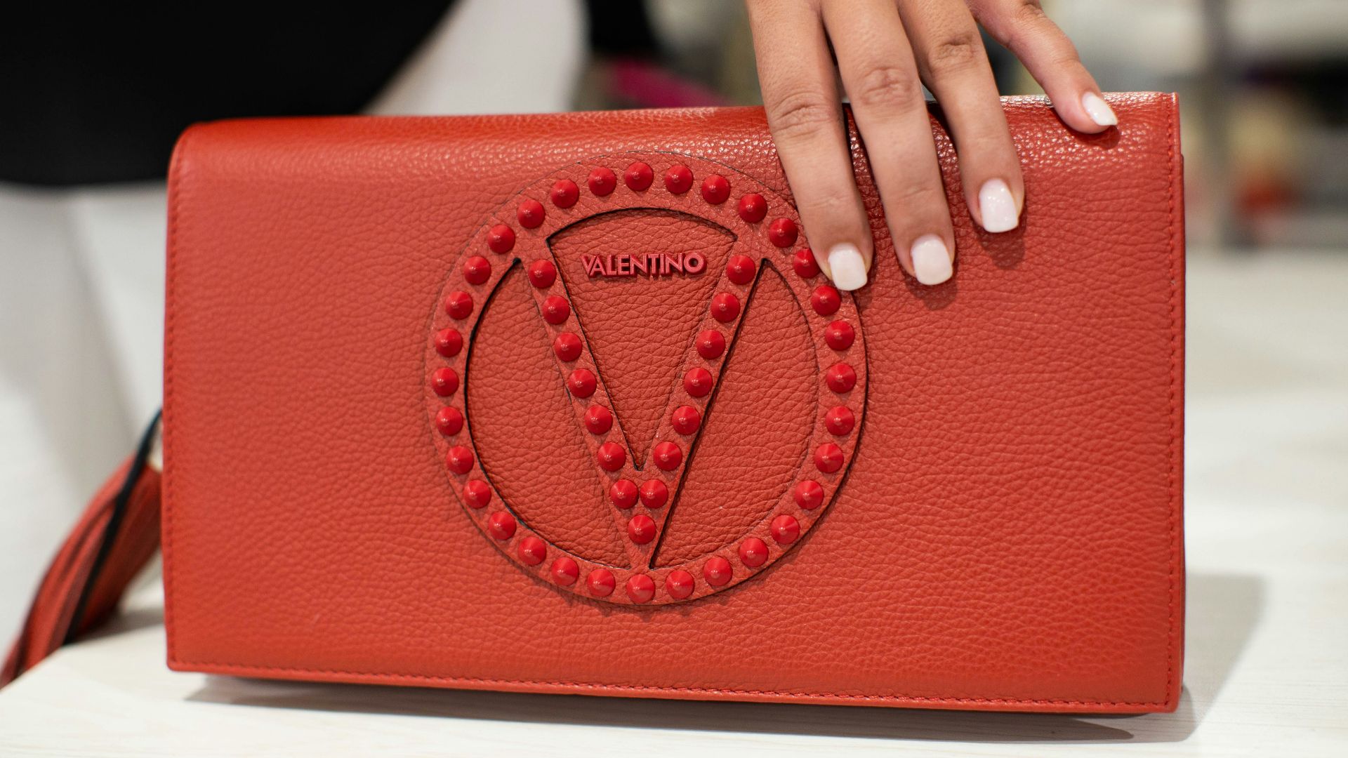 person holding red leather handbag