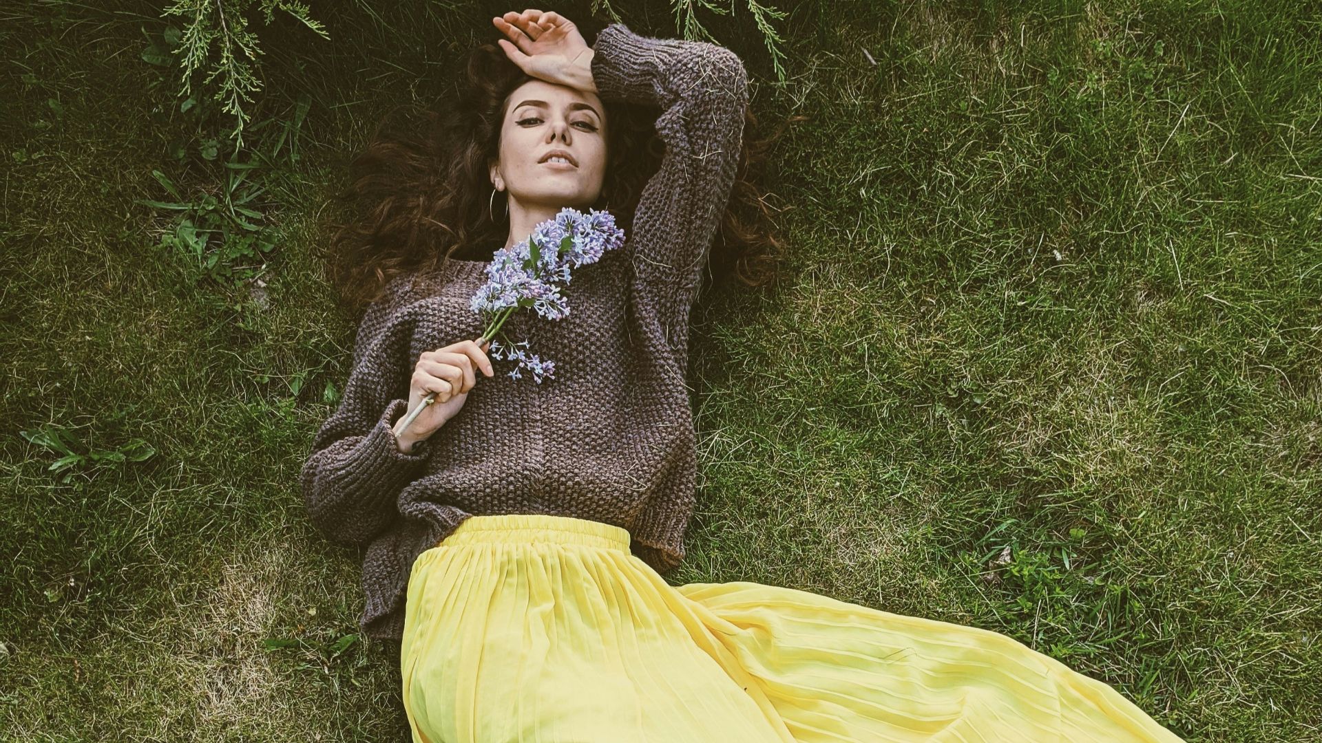 woman in black long sleeve shirt and yellow skirt sitting on green grass