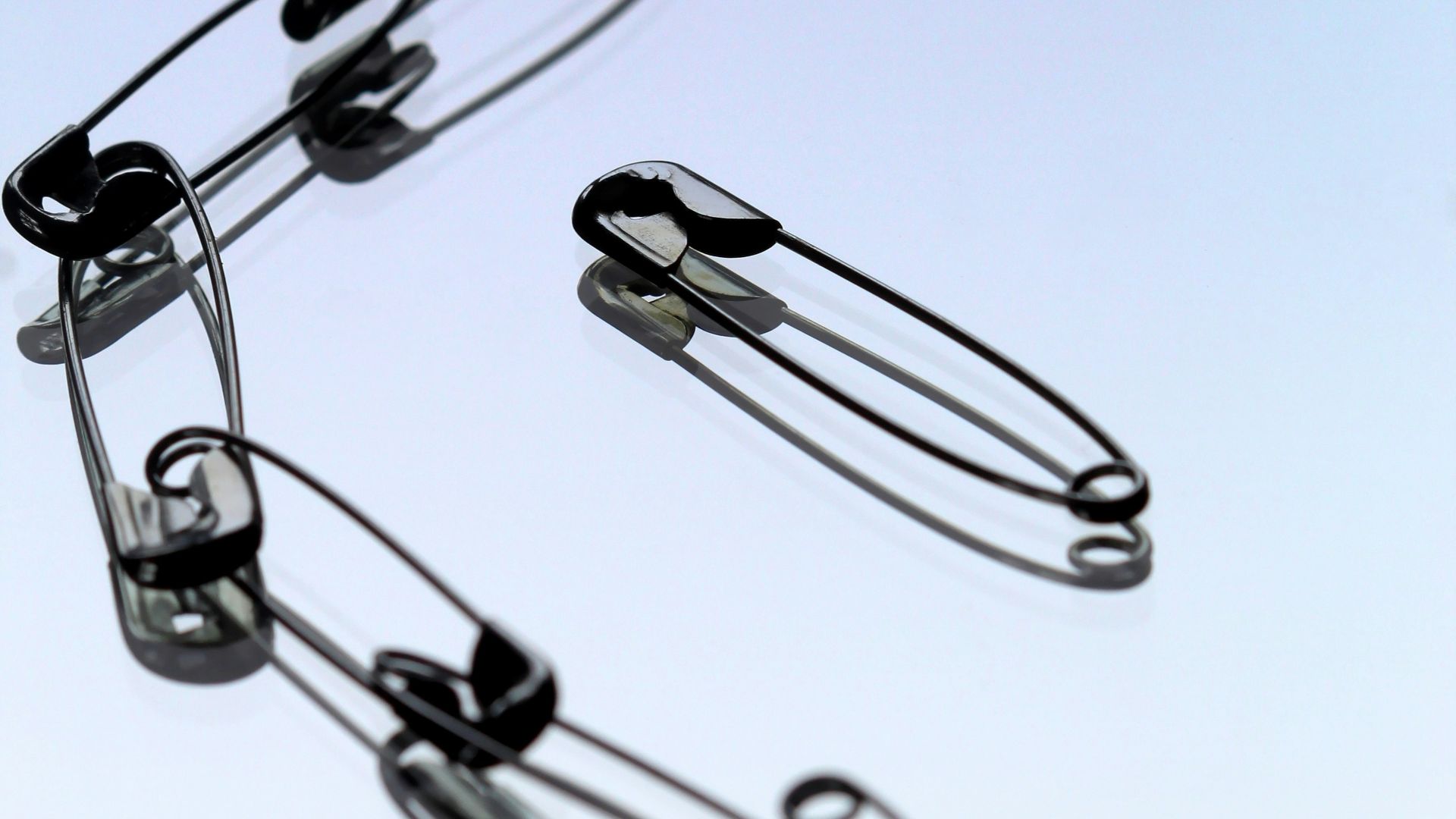 silver safety pin on white paper