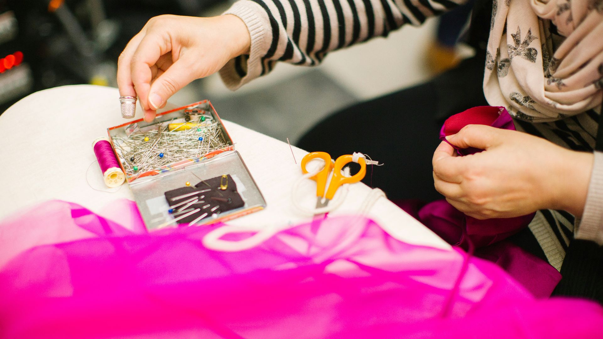 person holding pin using right hand and red mesh cloth using left hand