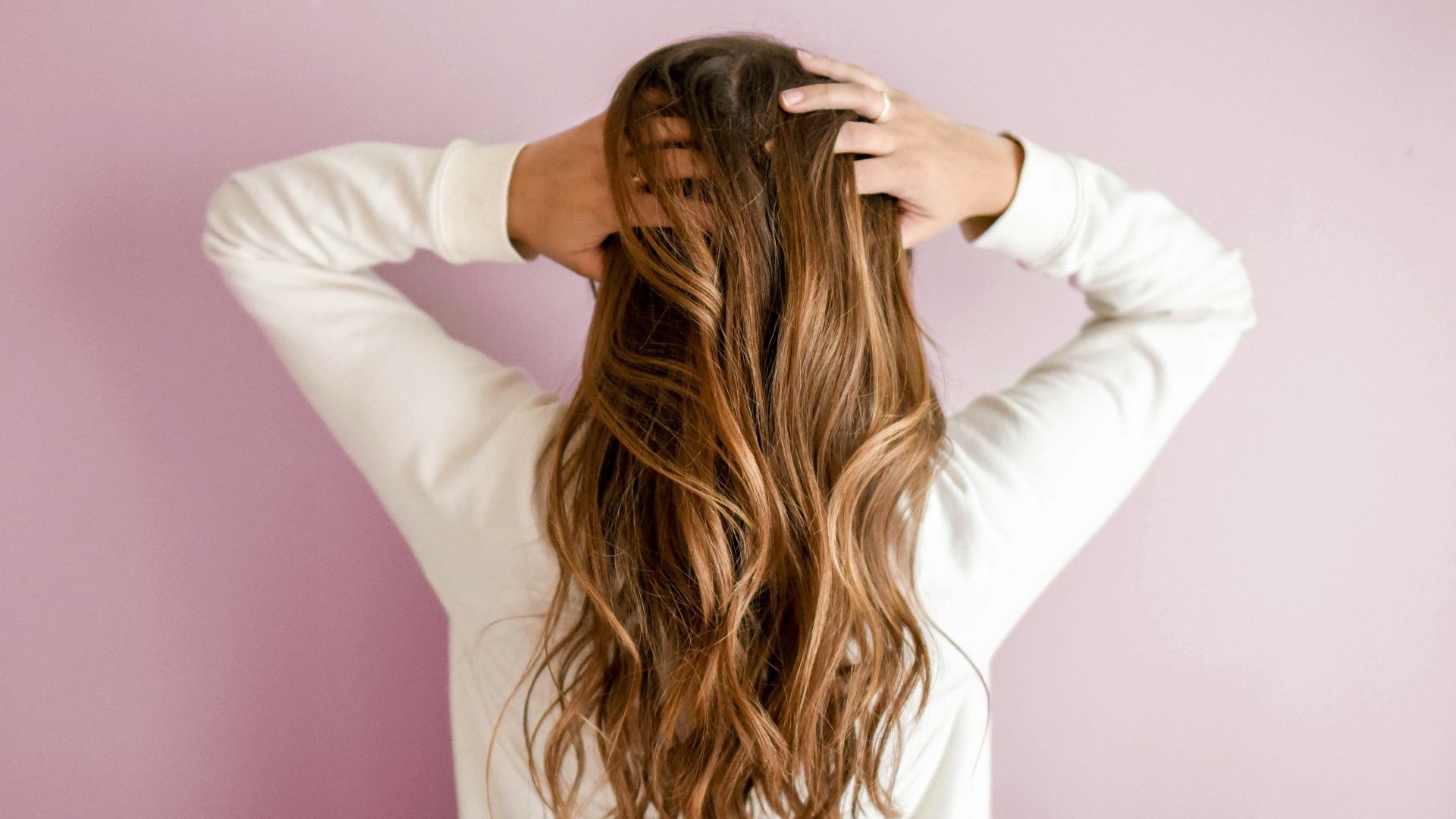 woman in white long-sleeved shirt standing in front of pink wall