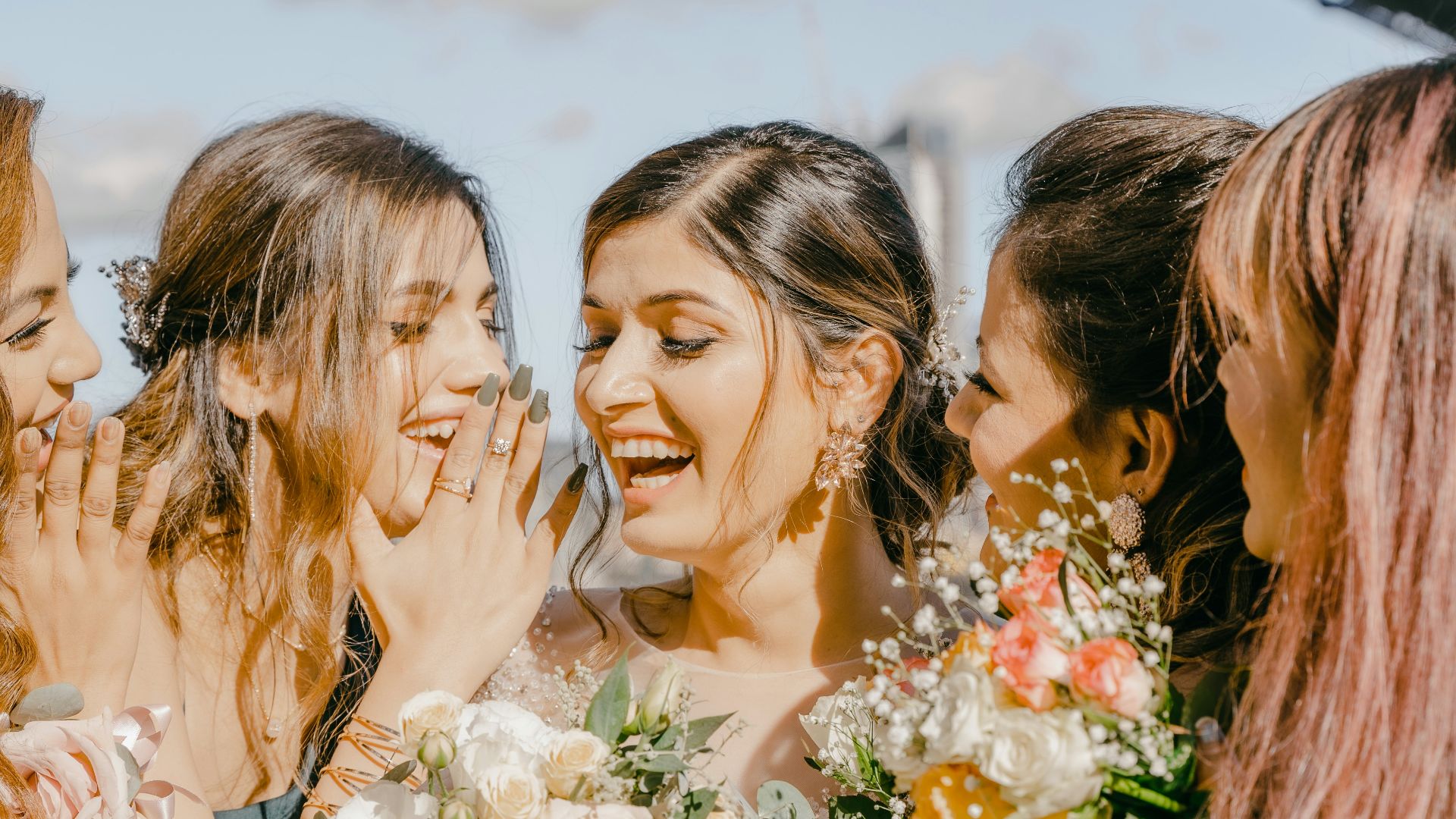 3 women in white floral dress holding bouquet of flowers