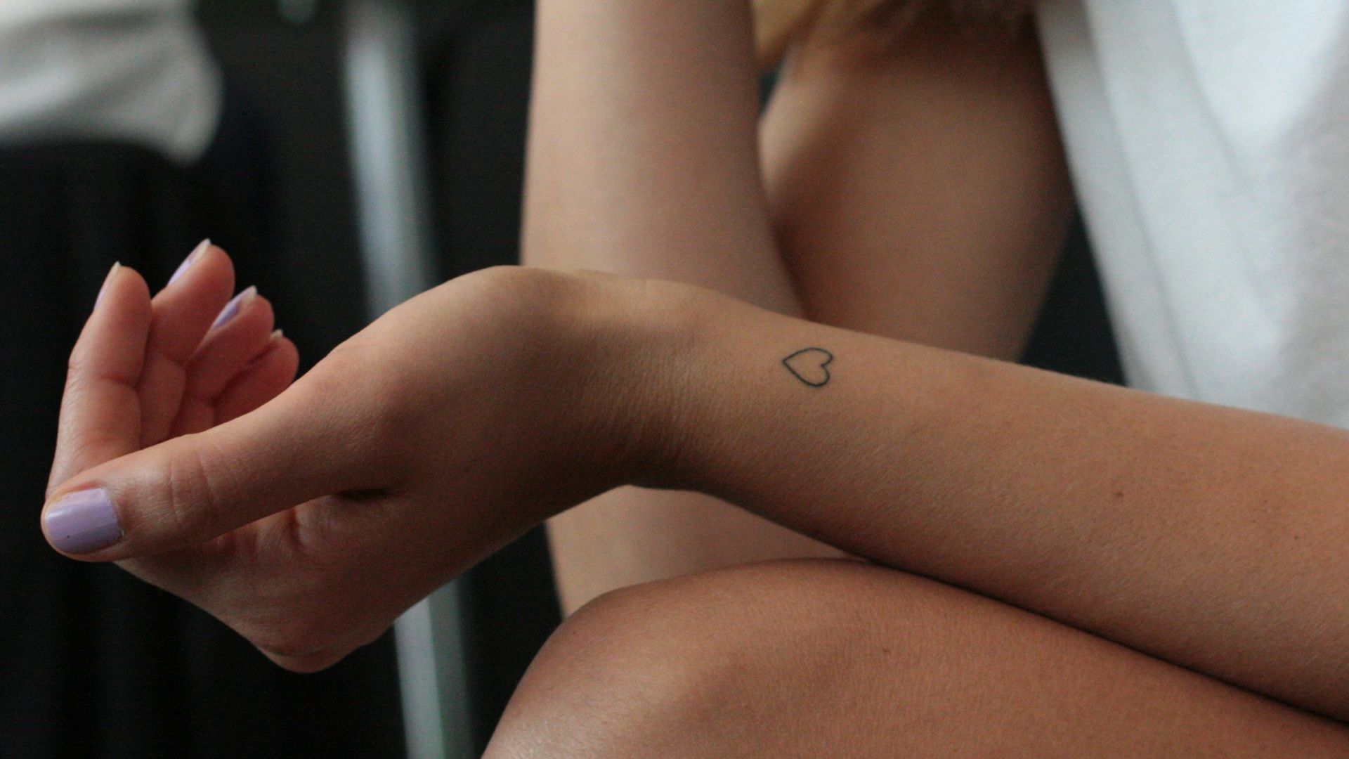 woman showing hear heart wrist tattoo