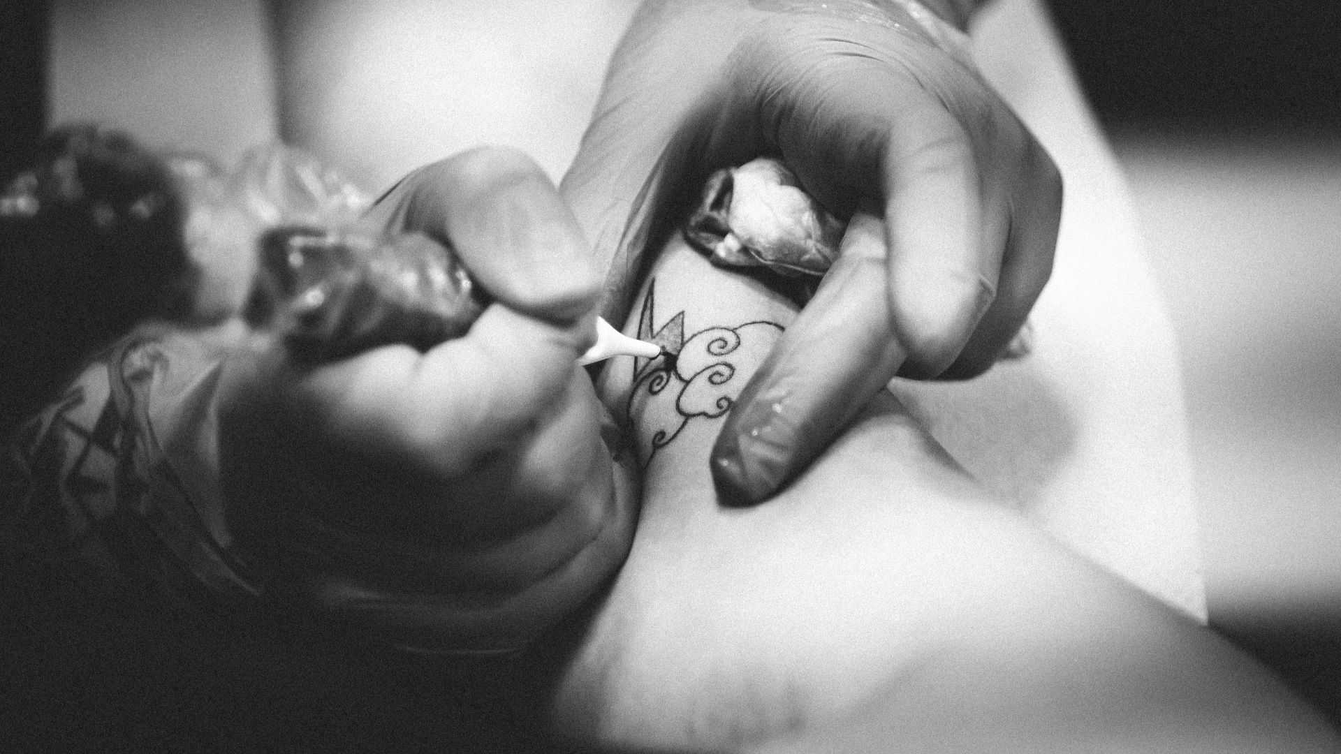 person doing flower tattoo on leg
