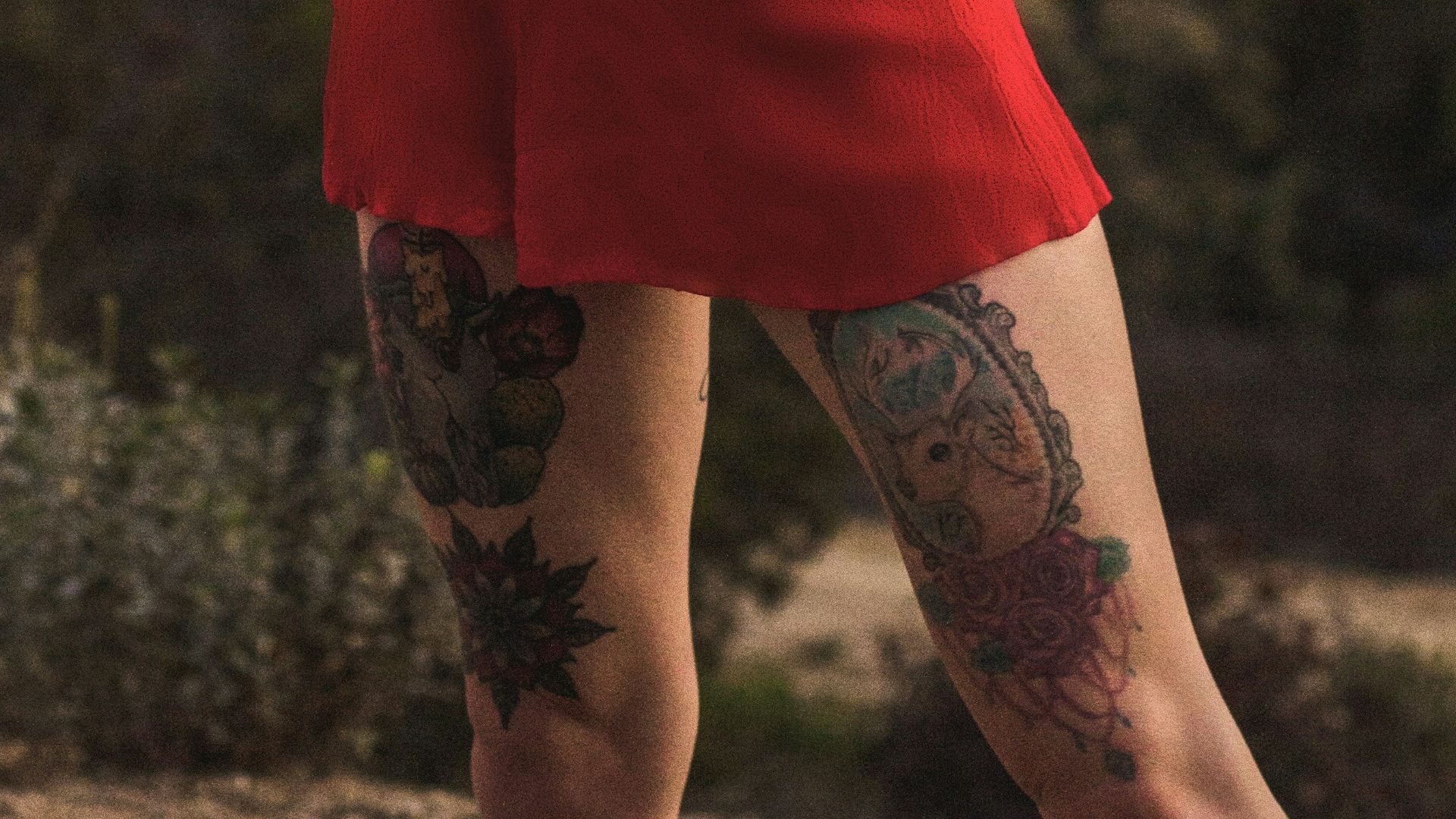 standing woman in red dress biting glasses