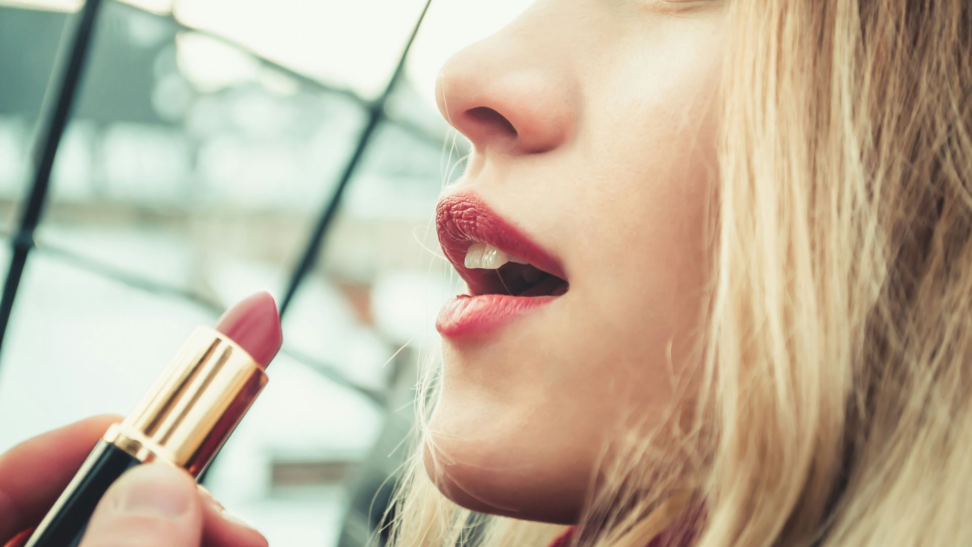 selective focus photography of woman holding lipstick