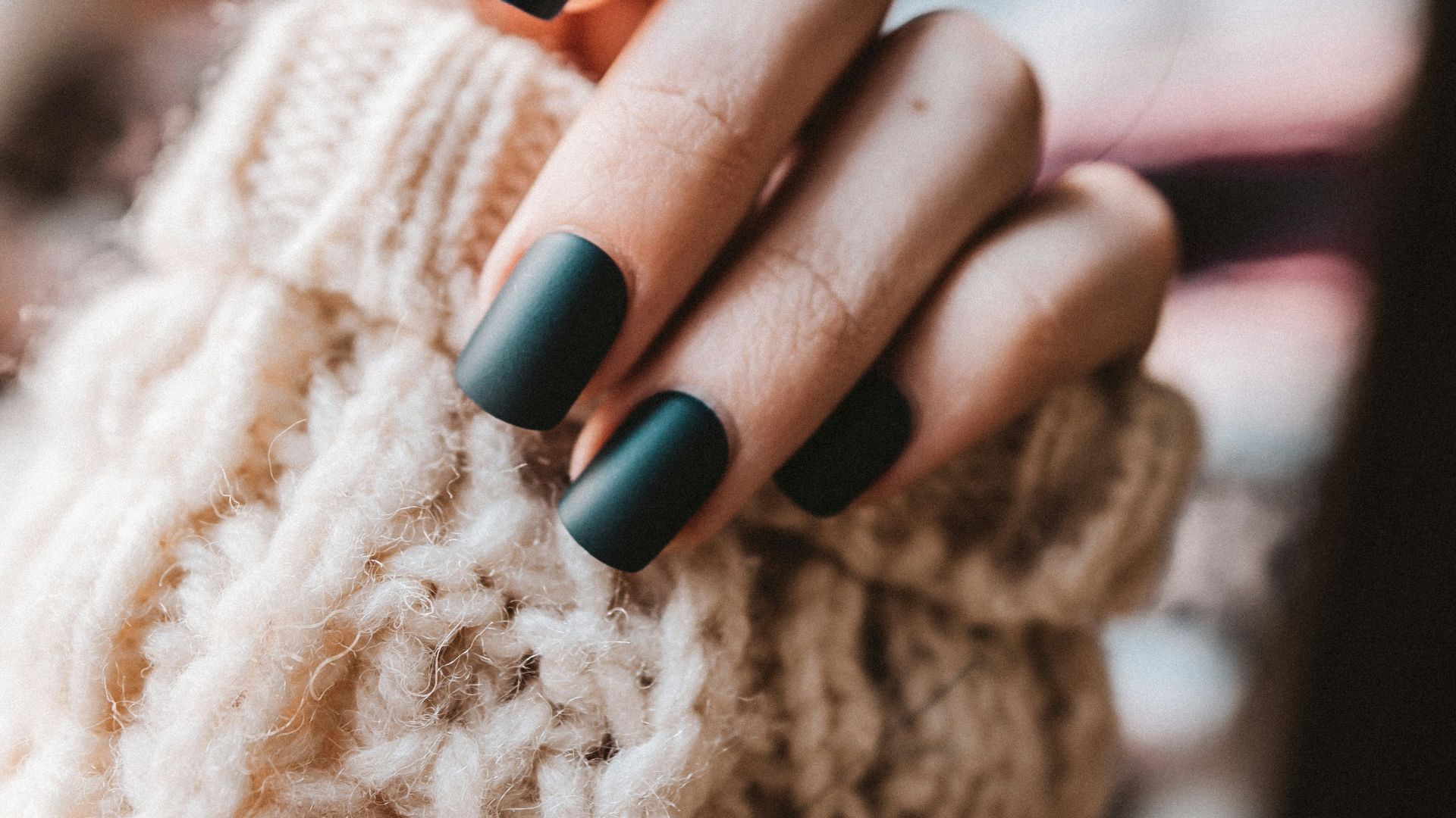person with black manicure holding white textile