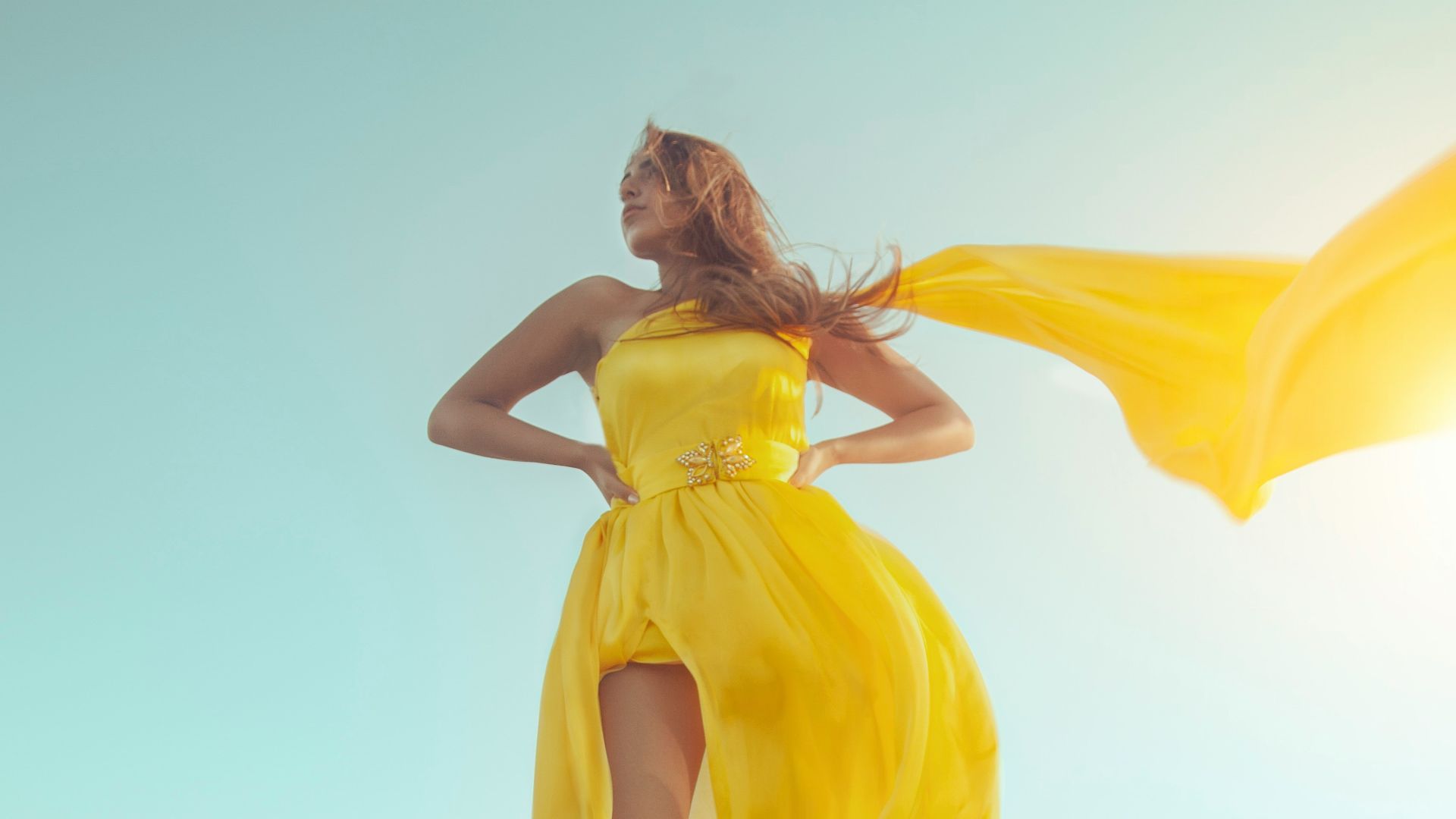 woman in yellow dress standing on brown sand during daytime