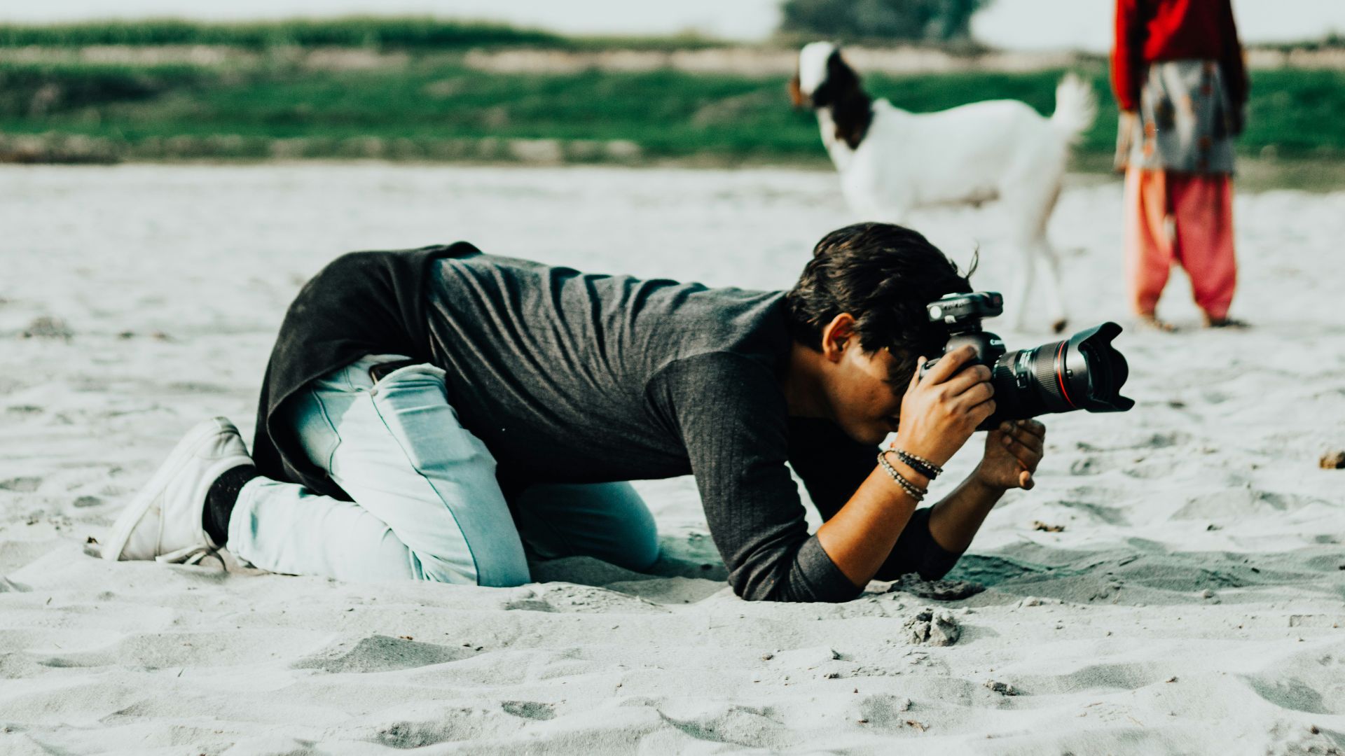 a man laying in the sand with a camera