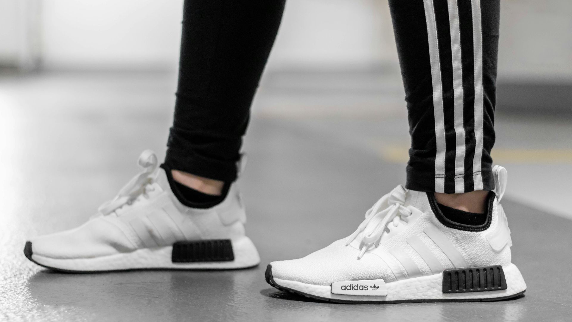 person wearing white Adidas NMD shoes