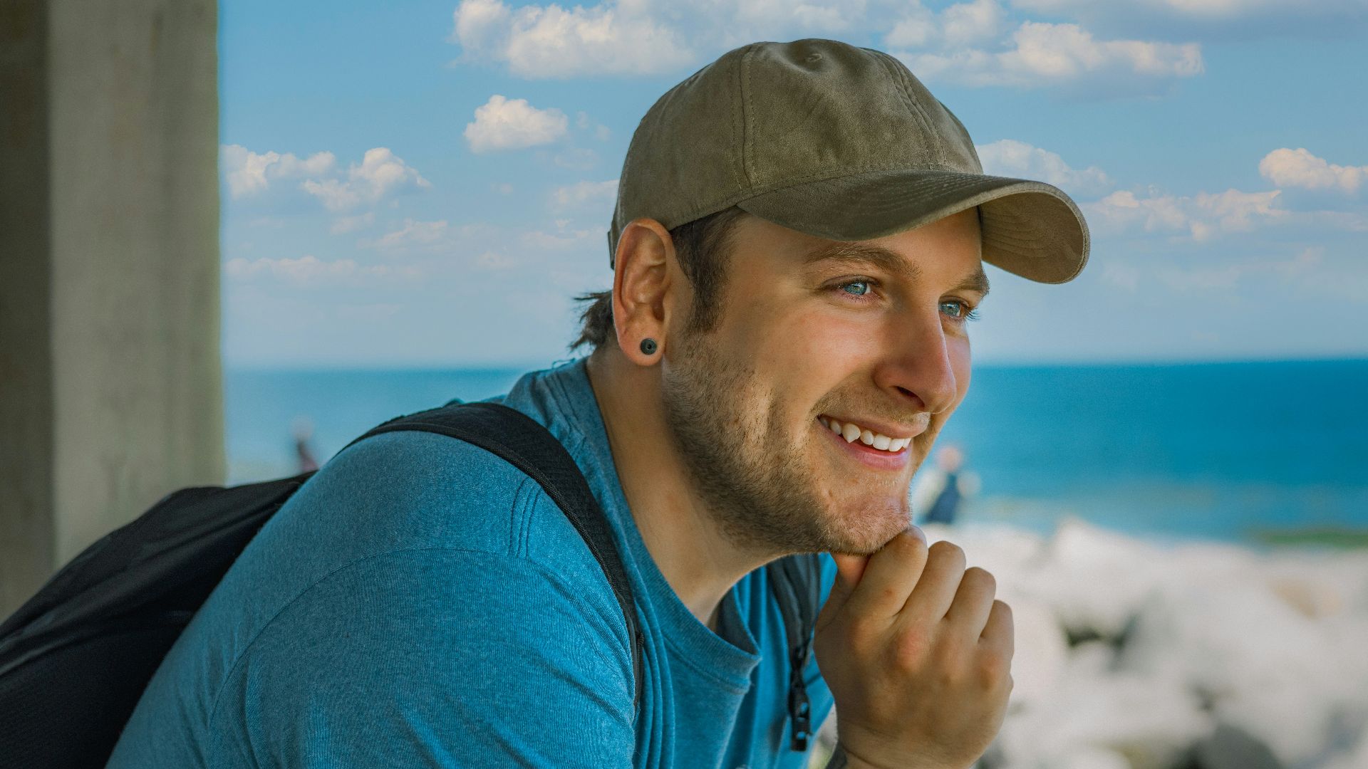 man in blue crew neck t-shirt wearing green and brown camouflage cap