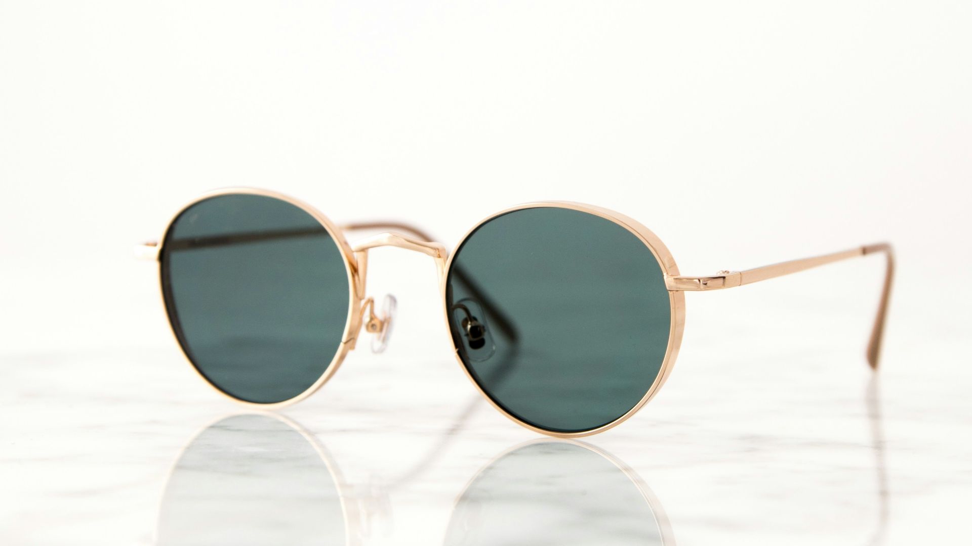 gold-colored framed hippie sunglasses on white surface