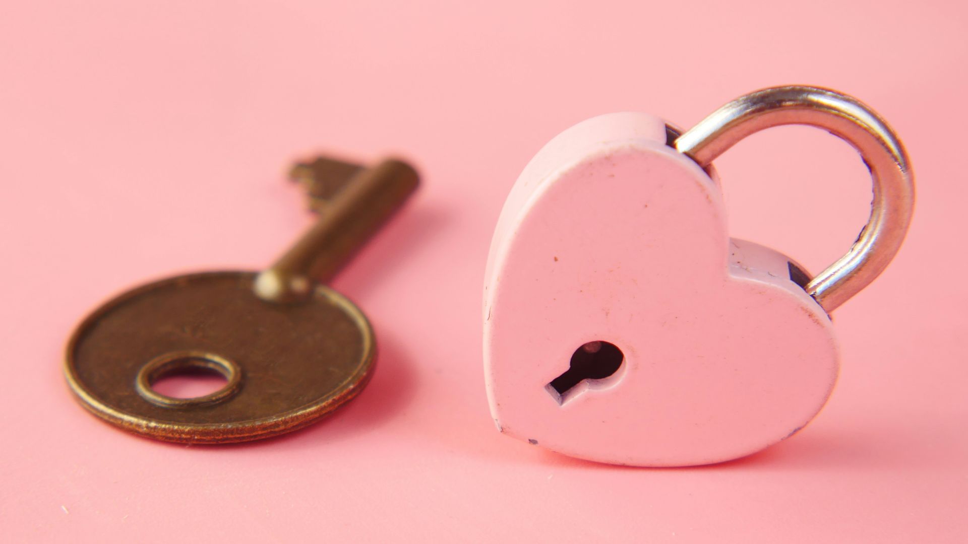a heart shaped lock and a key on a pink background