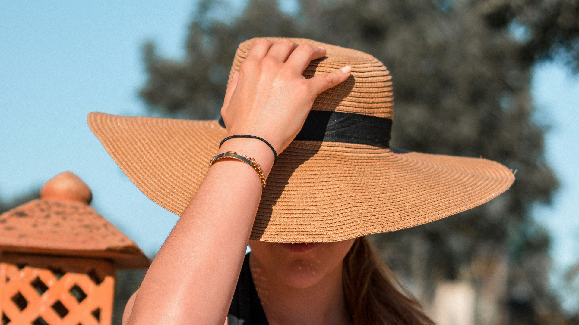 woman in black tank top and brown sun hat sitting on chair
