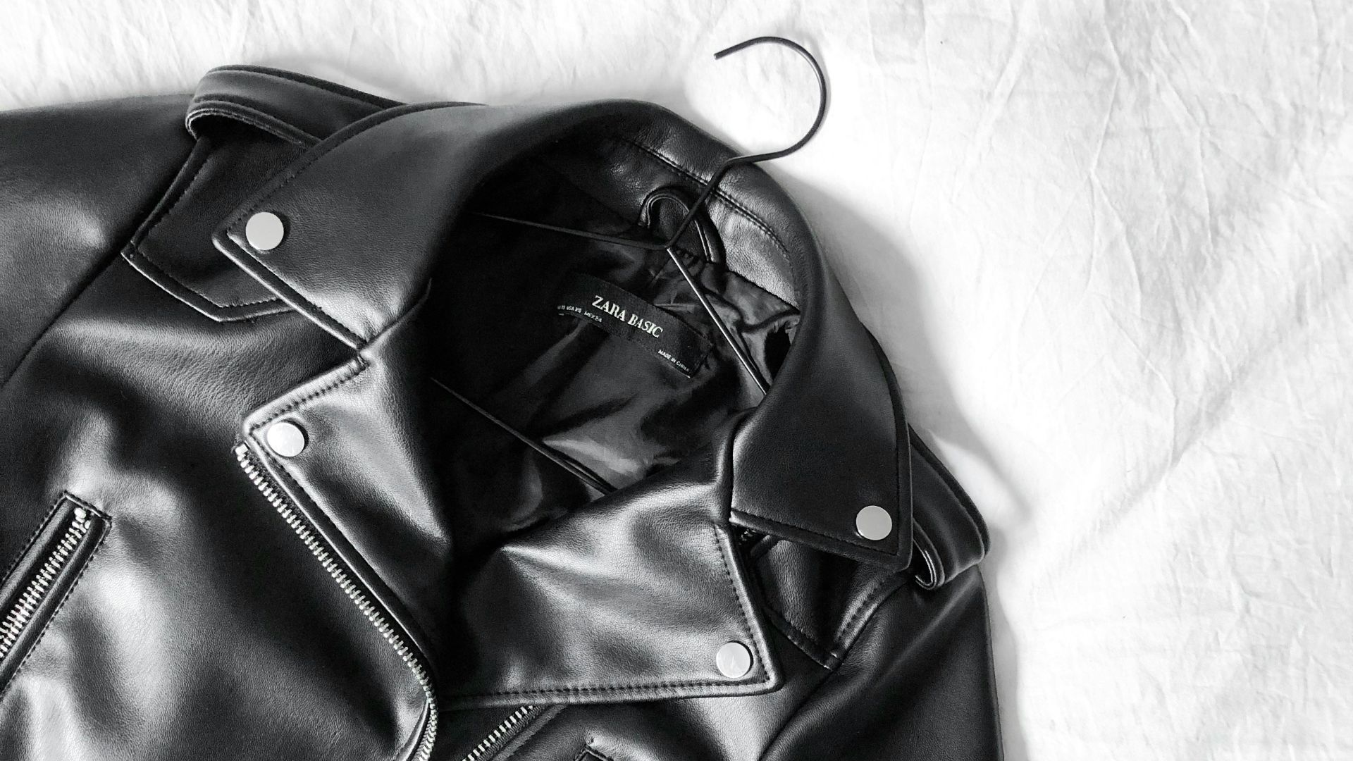 black leather zip-up jacket on white textile