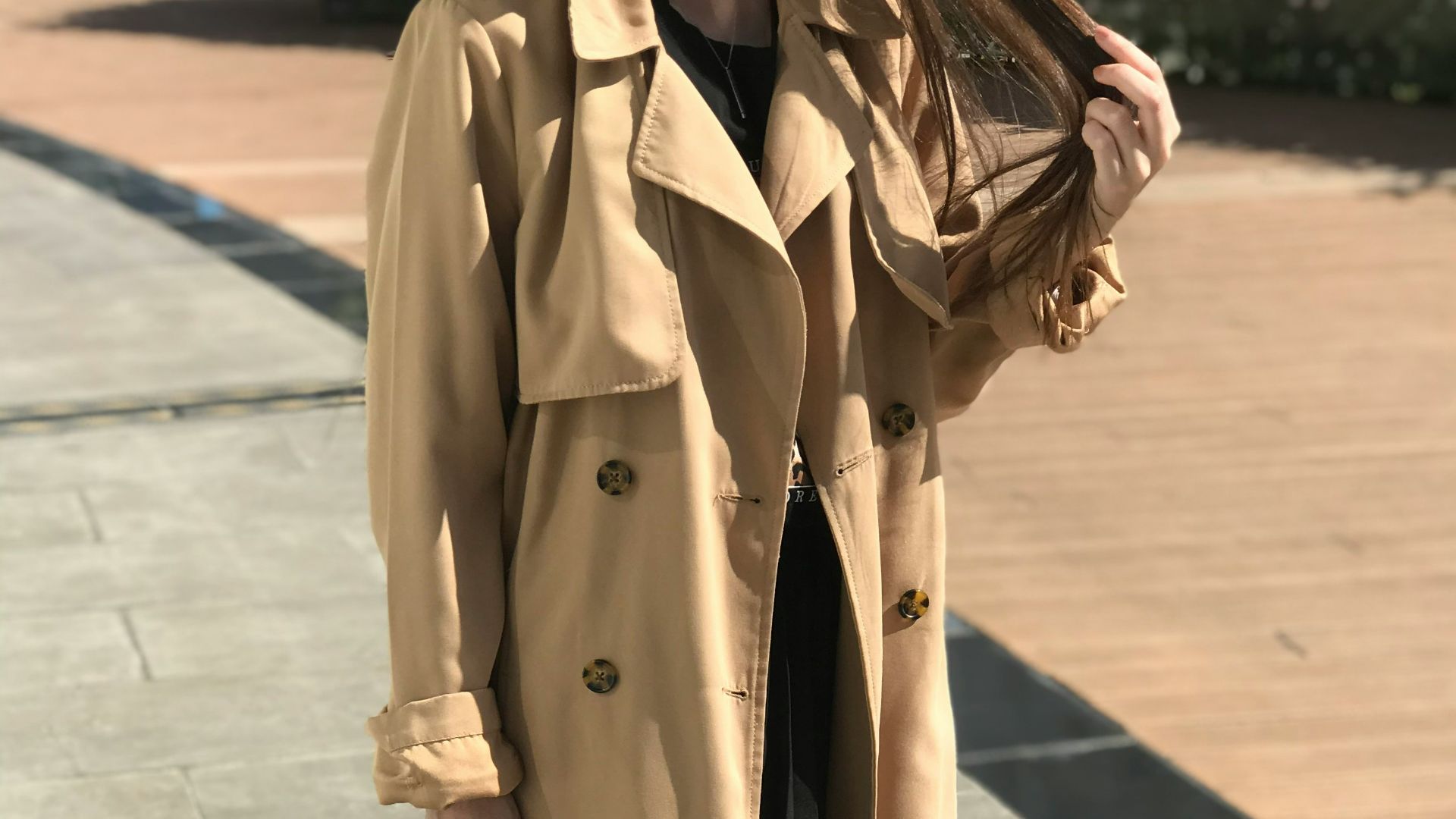 woman in brown coat and black leather sling bag