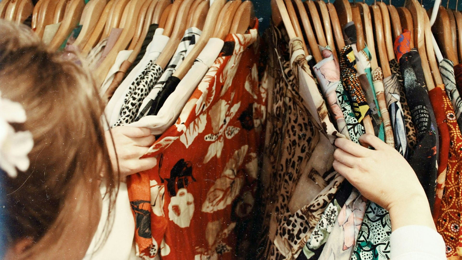 person holding assorted clothes in wooden hanger