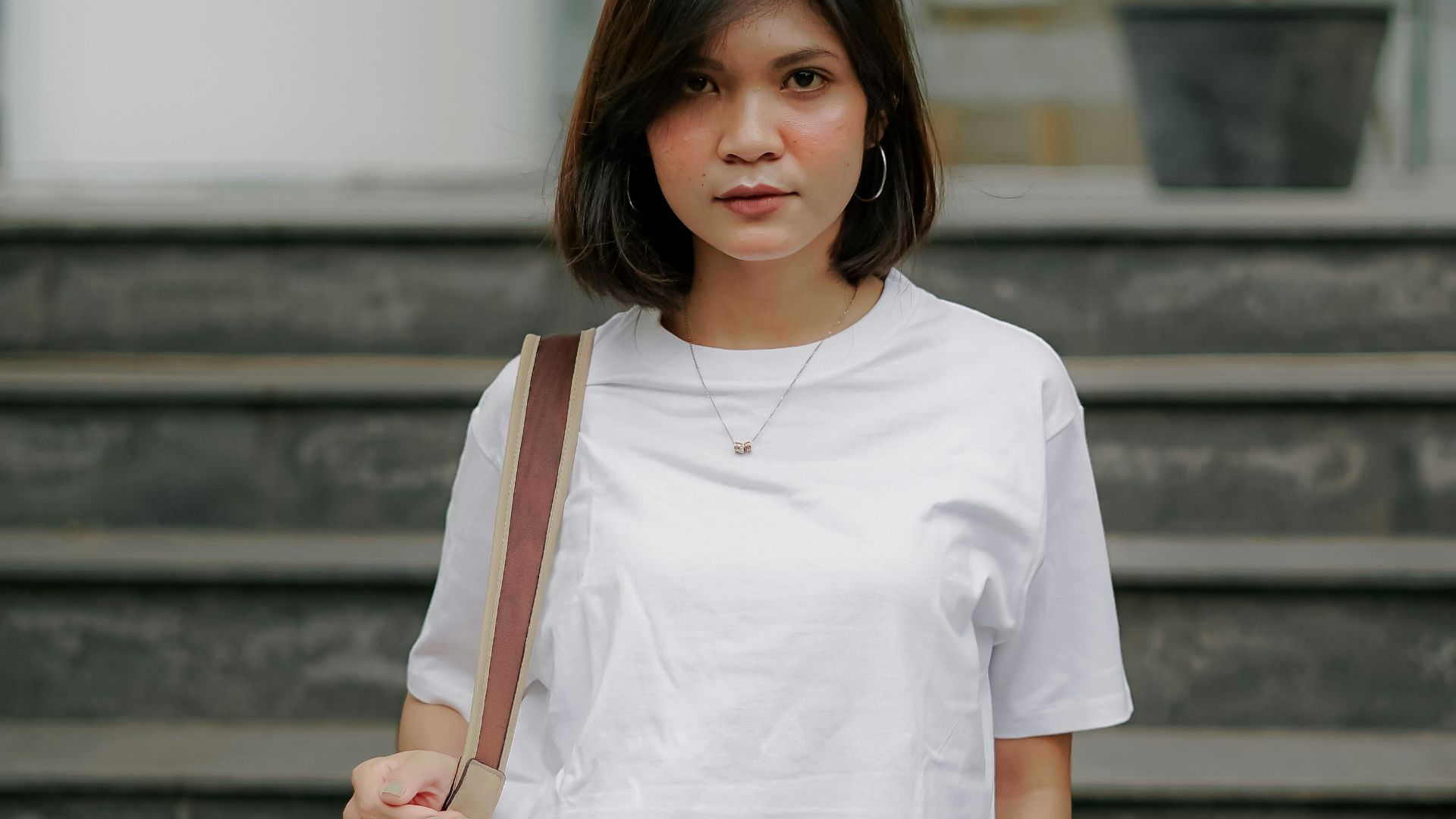 woman in white crew neck t-shirt and brown leather sling bag