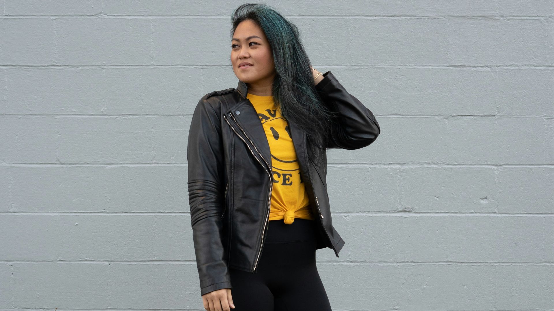 woman in black jacket and black pants standing beside white wall