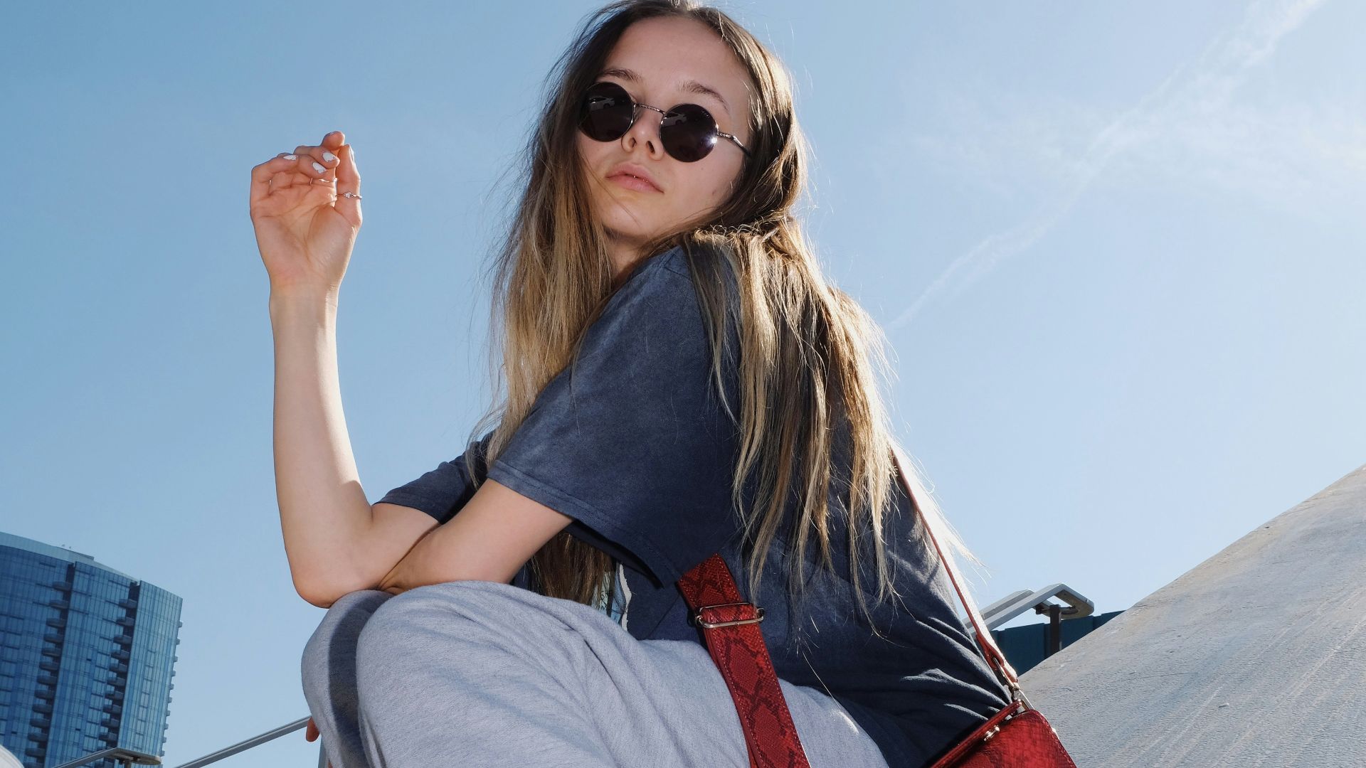 woman in gray t-shirt and gray pants sitting on gray concrete bench during daytime