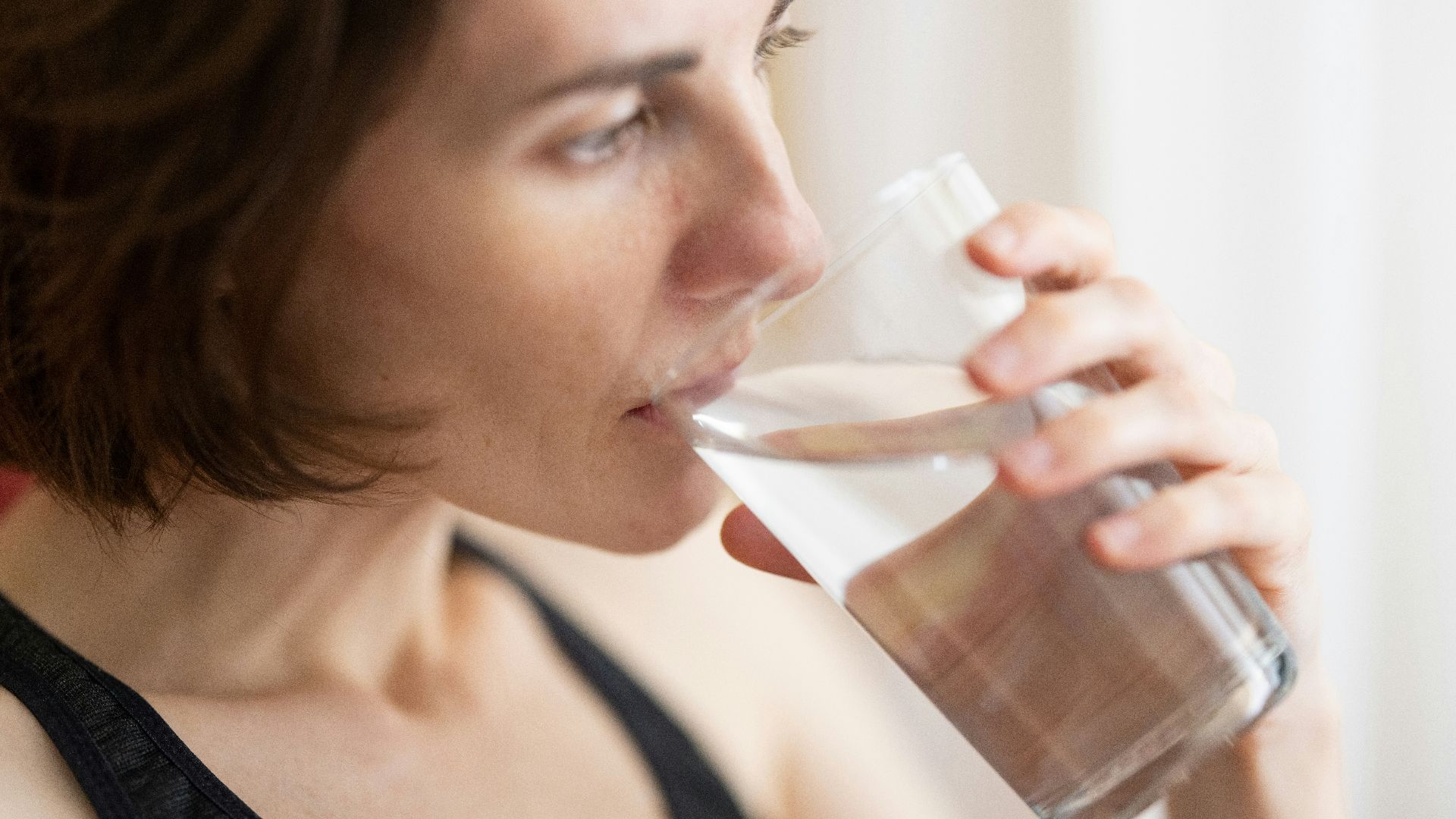 woman in black tank top drinking water
