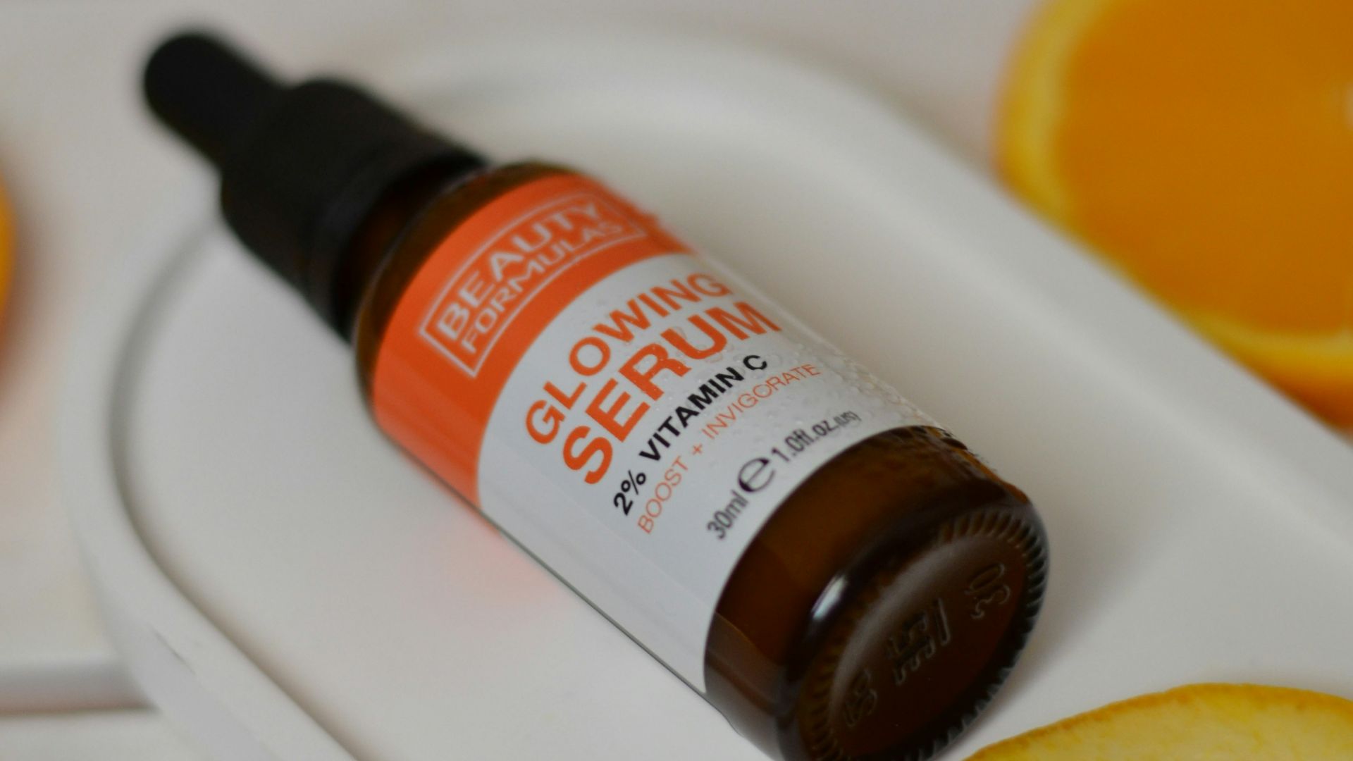 A bottle of vitamin oil sitting on top of an orange