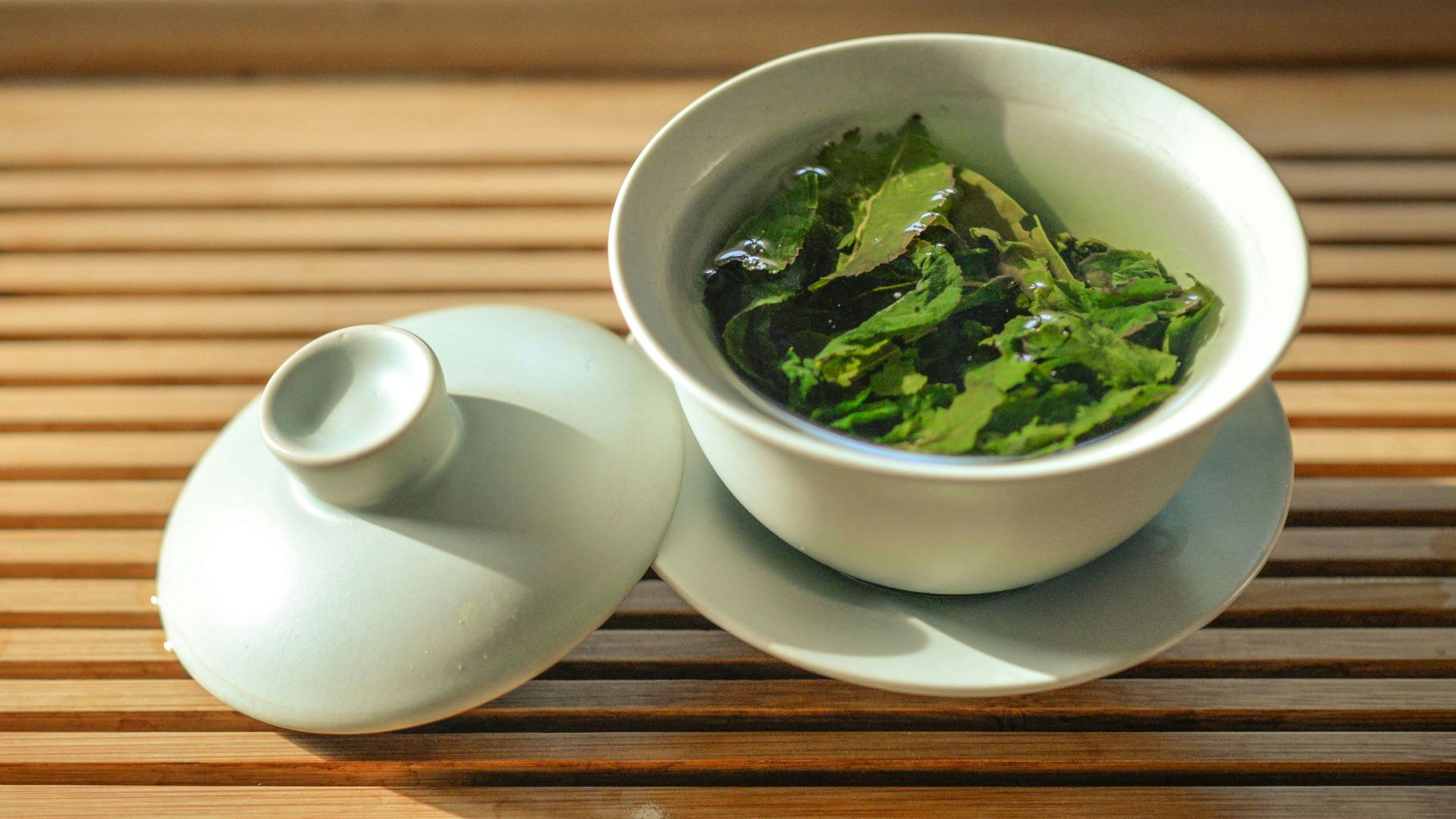 green tea leaves in white ceramic bowl with open lid