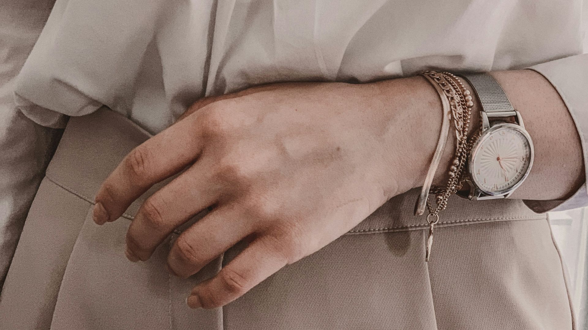 person in white dress shirt wearing silver link bracelet round analog watch