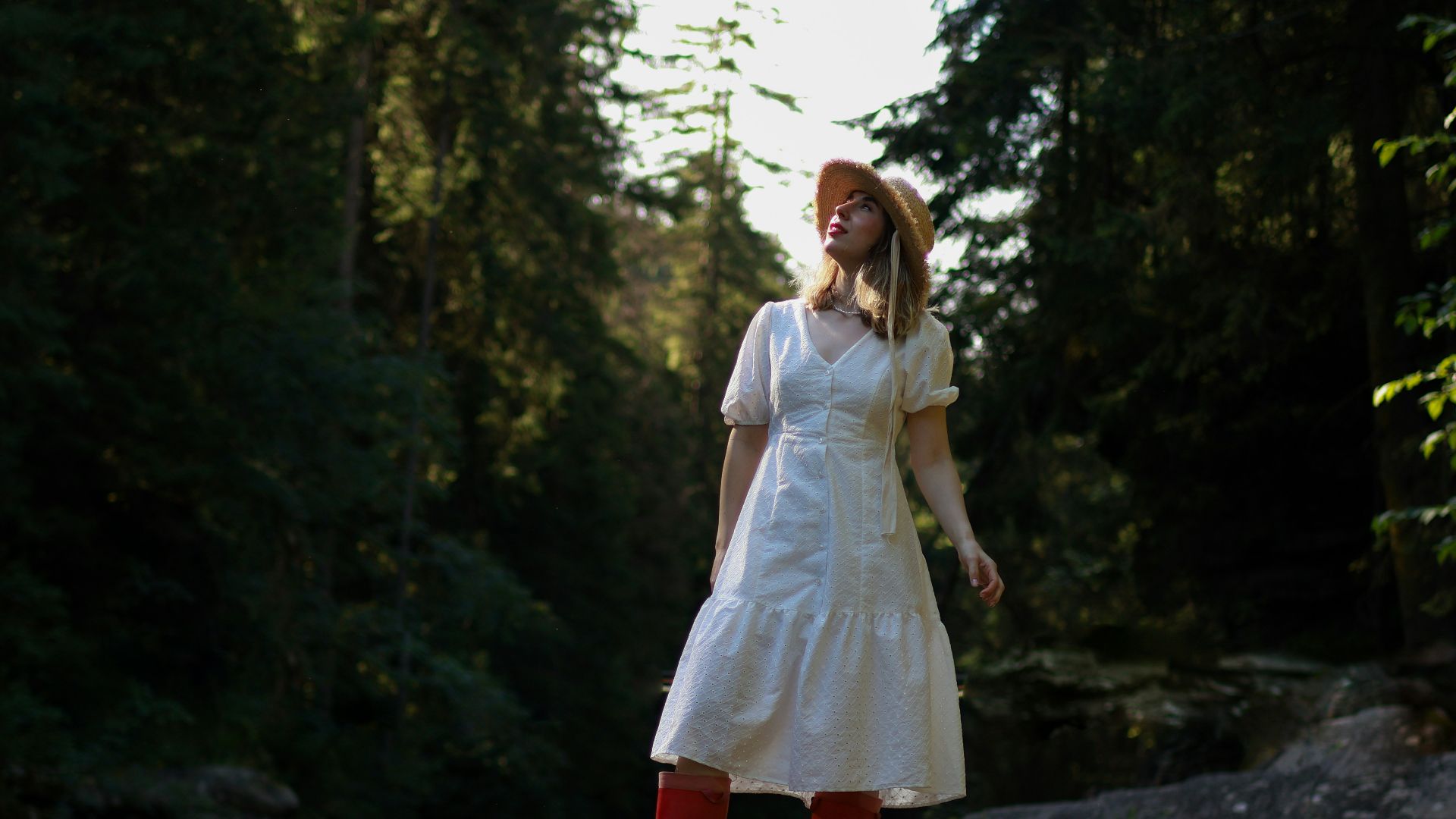 a woman in a white dress and red boots standing on a rock