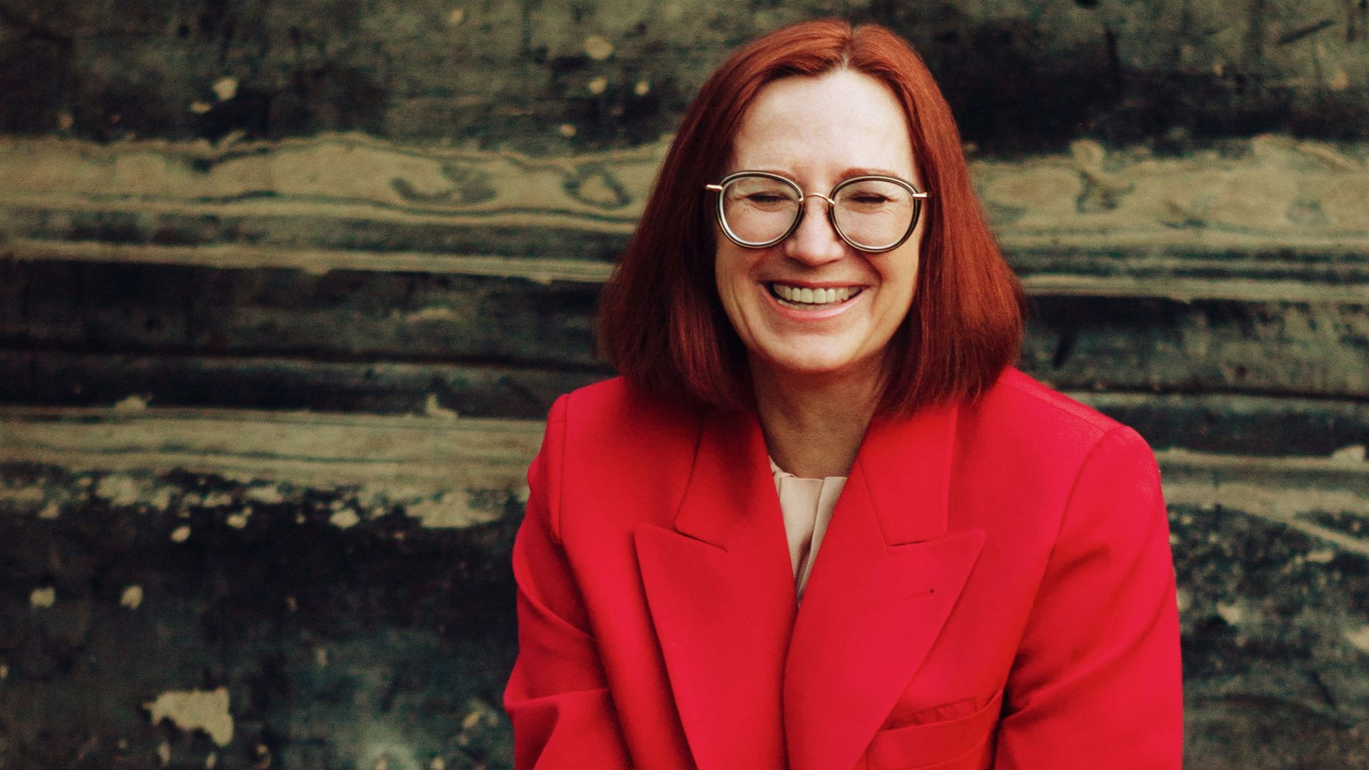 woman in red blazer and black skirt sitting on brown concrete stairs