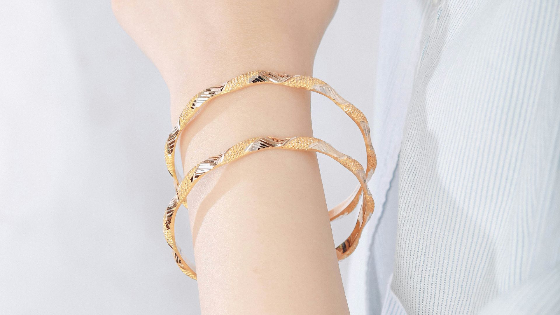 A woman's arm displays two gold bracelets.