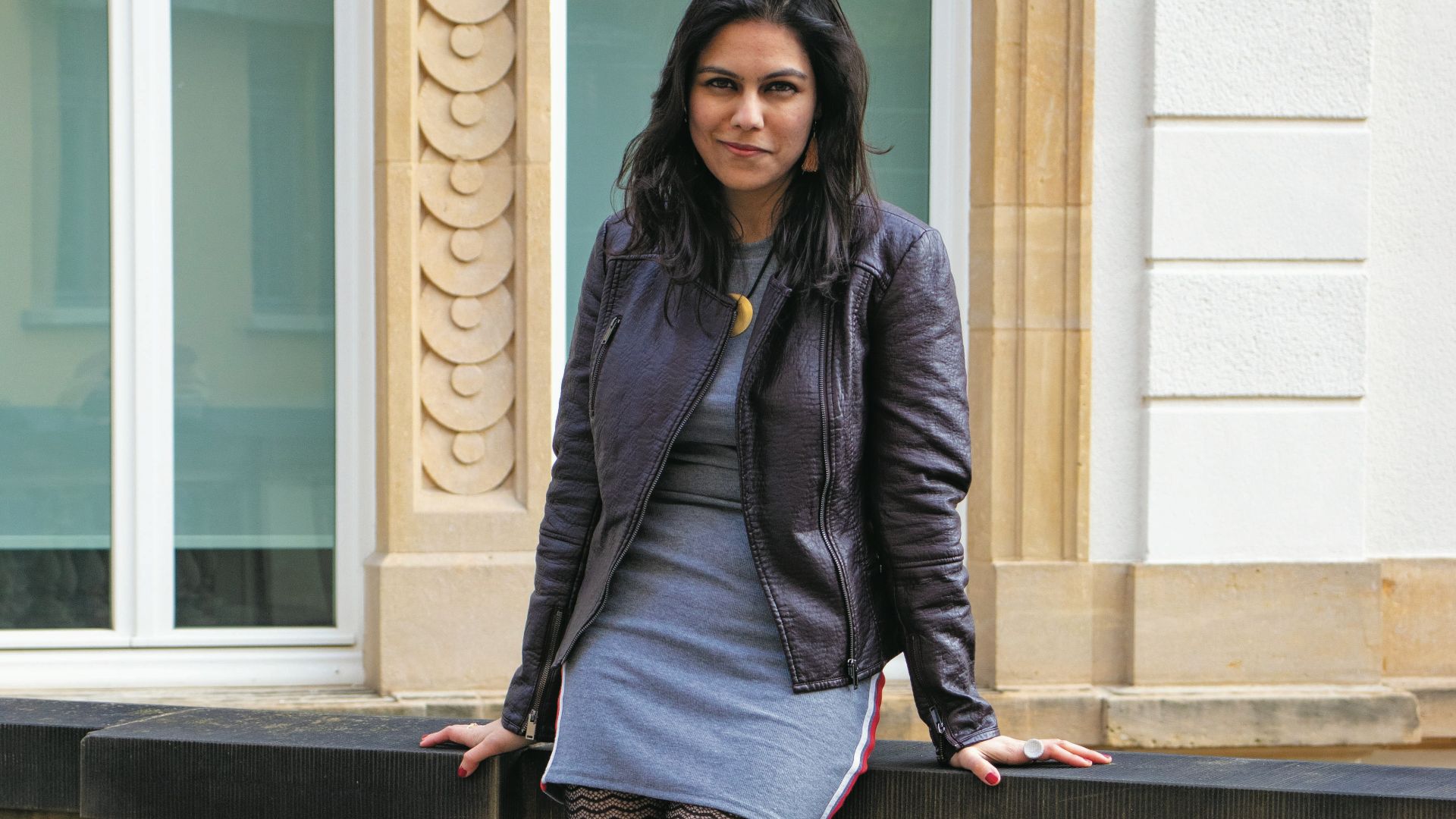 woman in purple coat and black skirt standing on gray concrete stairs