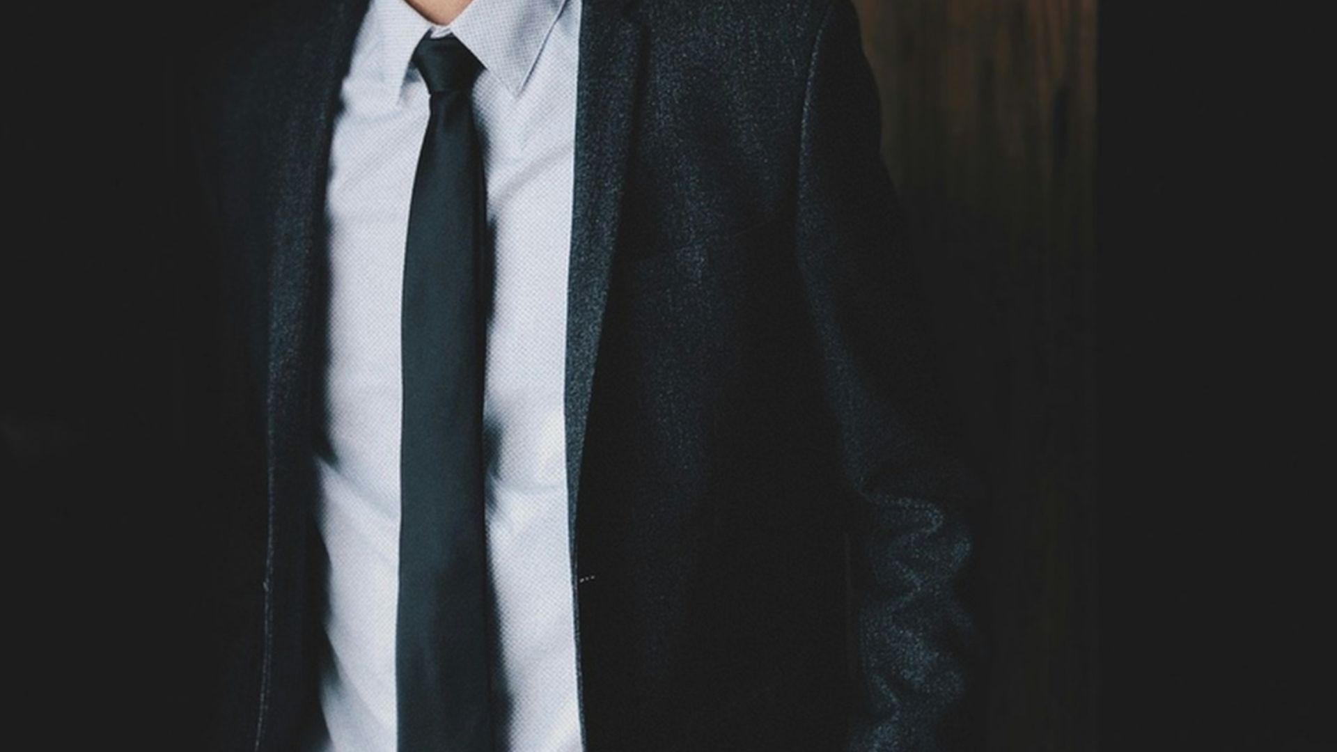 a man in a suit and tie standing in a dark room