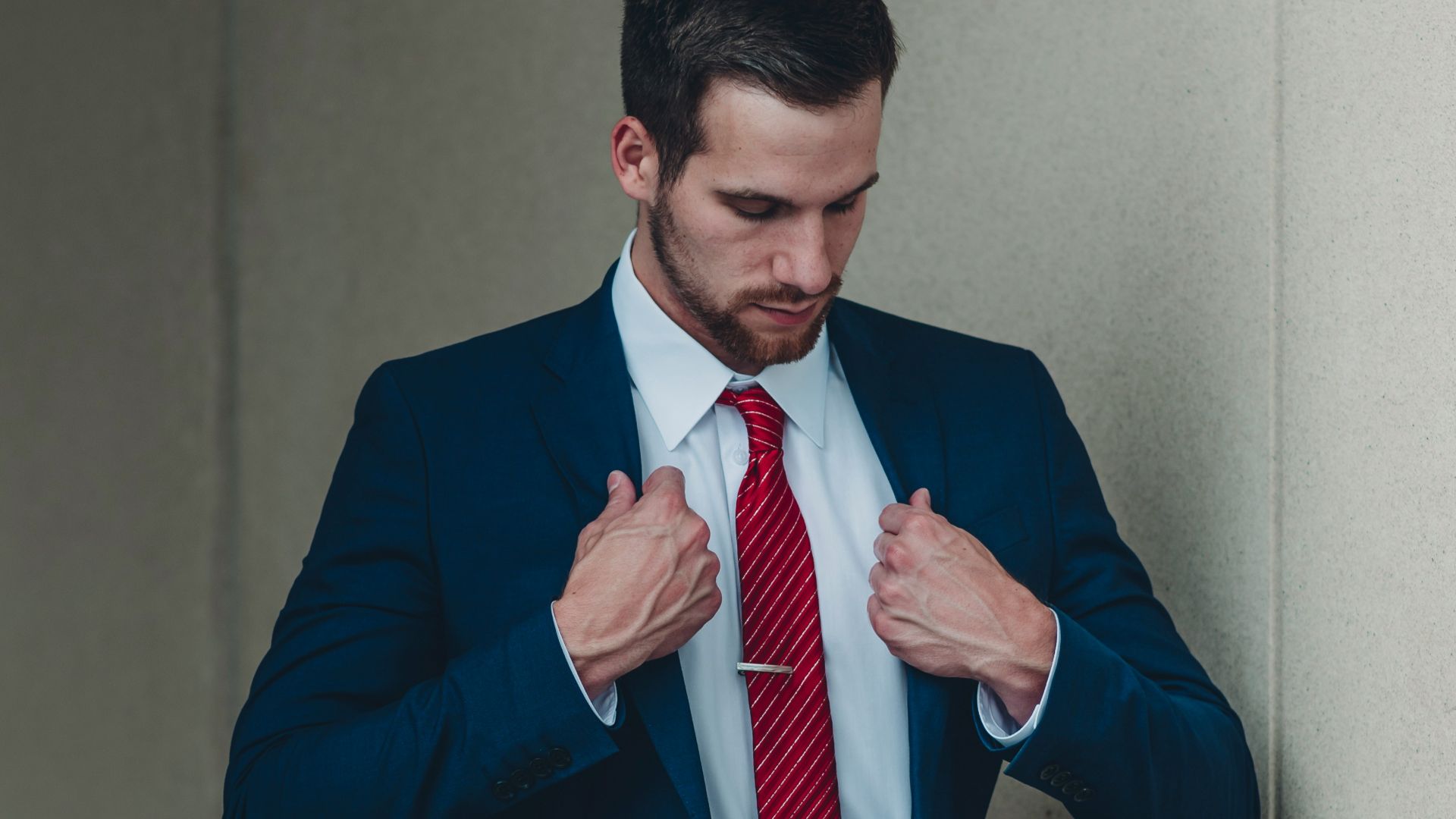 a man in a suit and red tie tying his tie