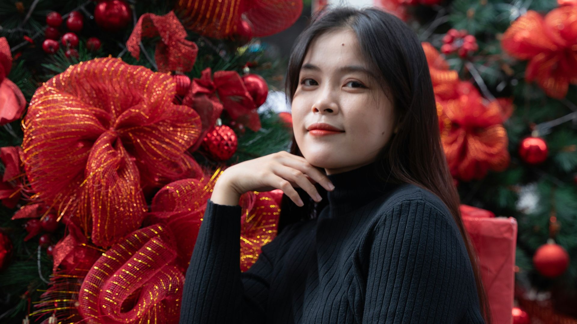 a woman sitting on a chair in front of a christmas tree