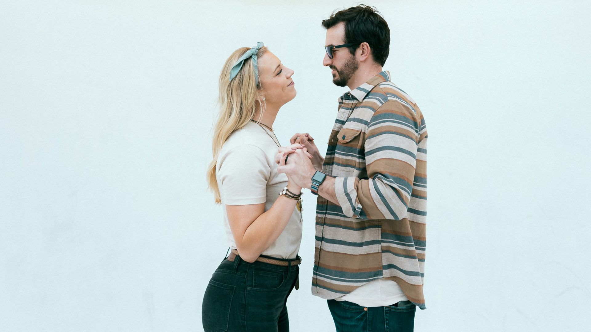 man and woman kissing beside yellow wall