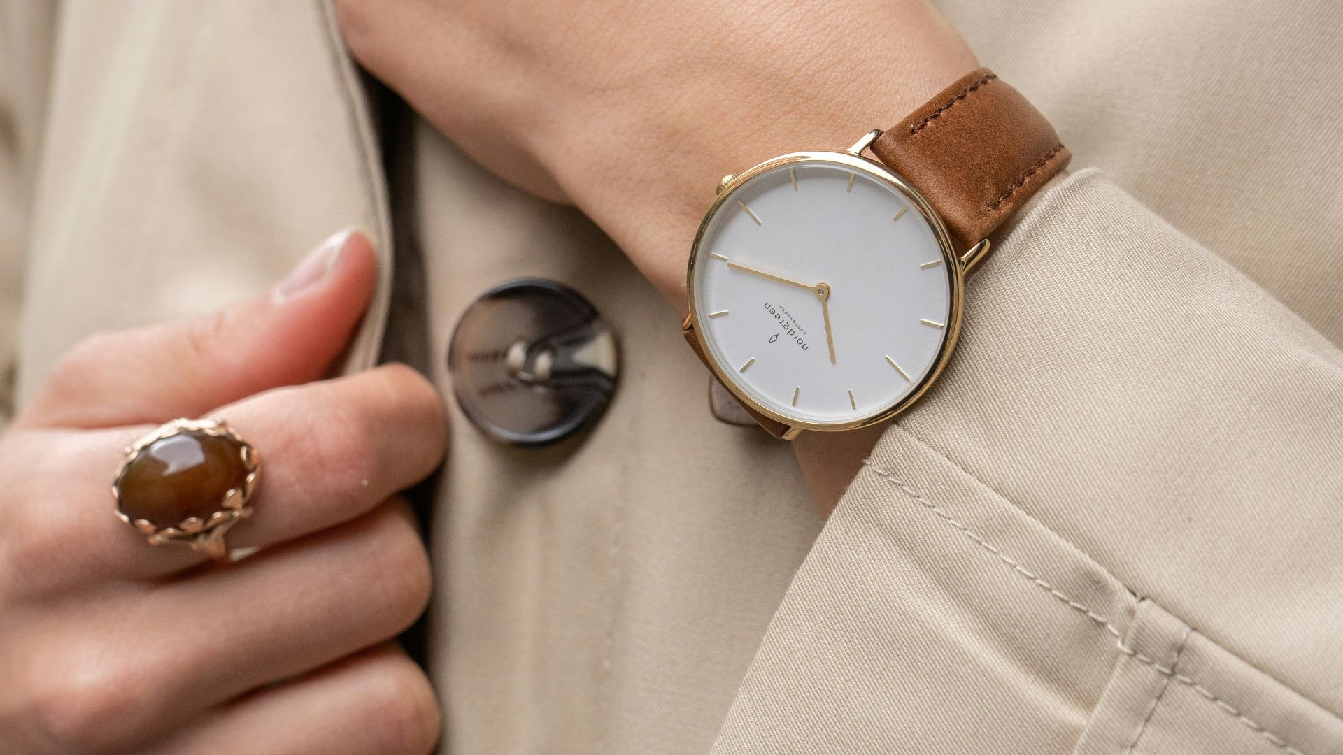 a woman wearing a trench coat and a watch