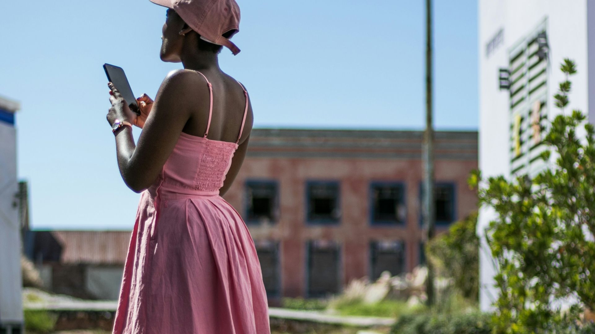 woman in pink spaghetti-strap mini dress using smartphone