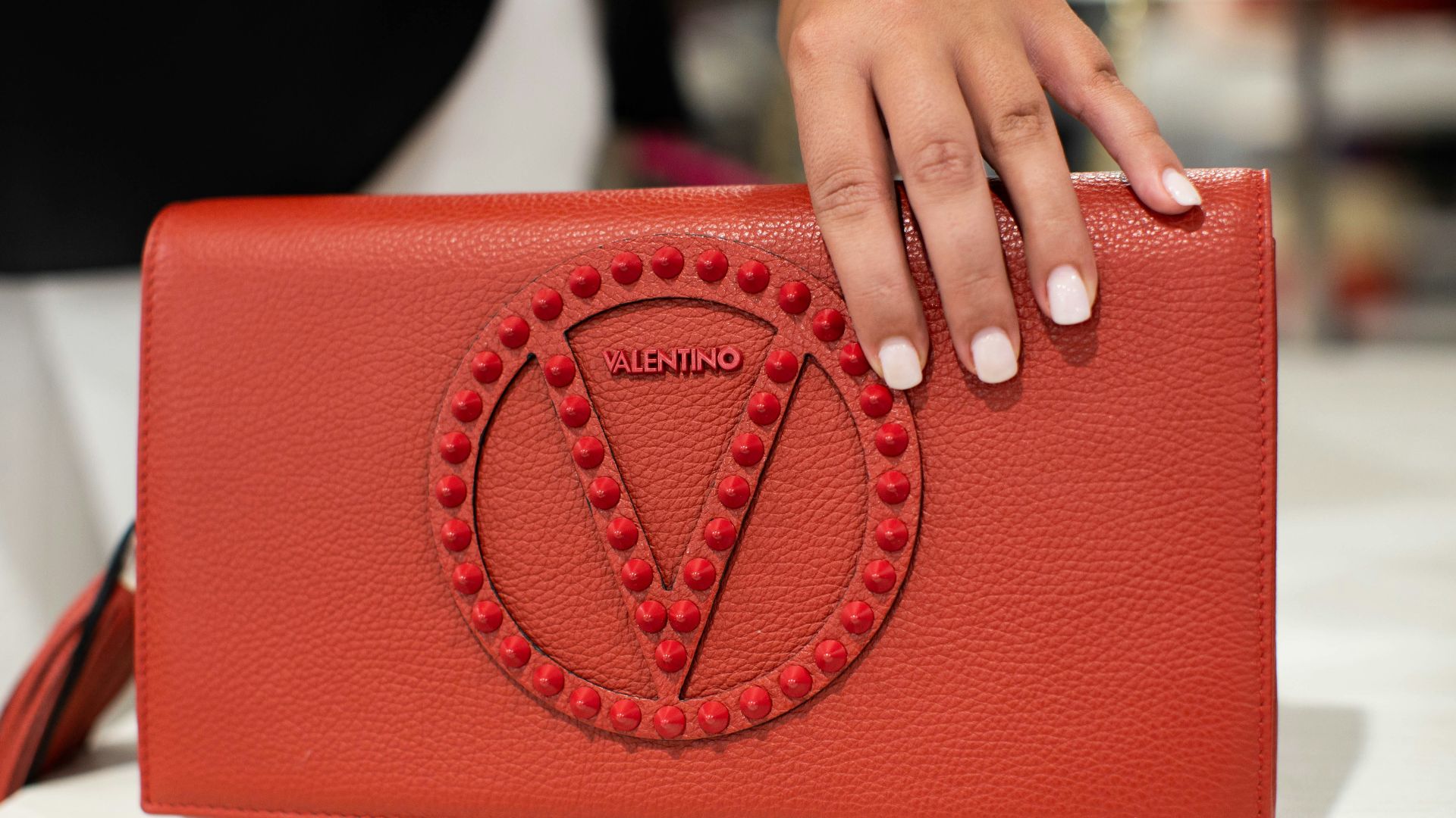 person holding red leather handbag