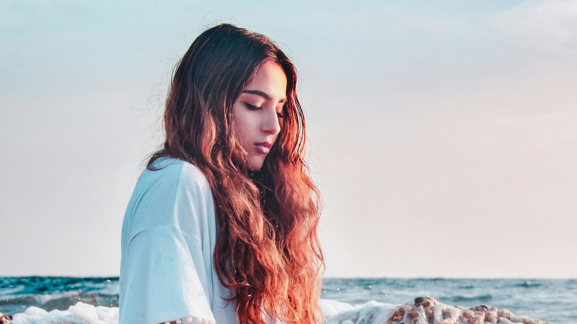 woman sitting at the rocky shore