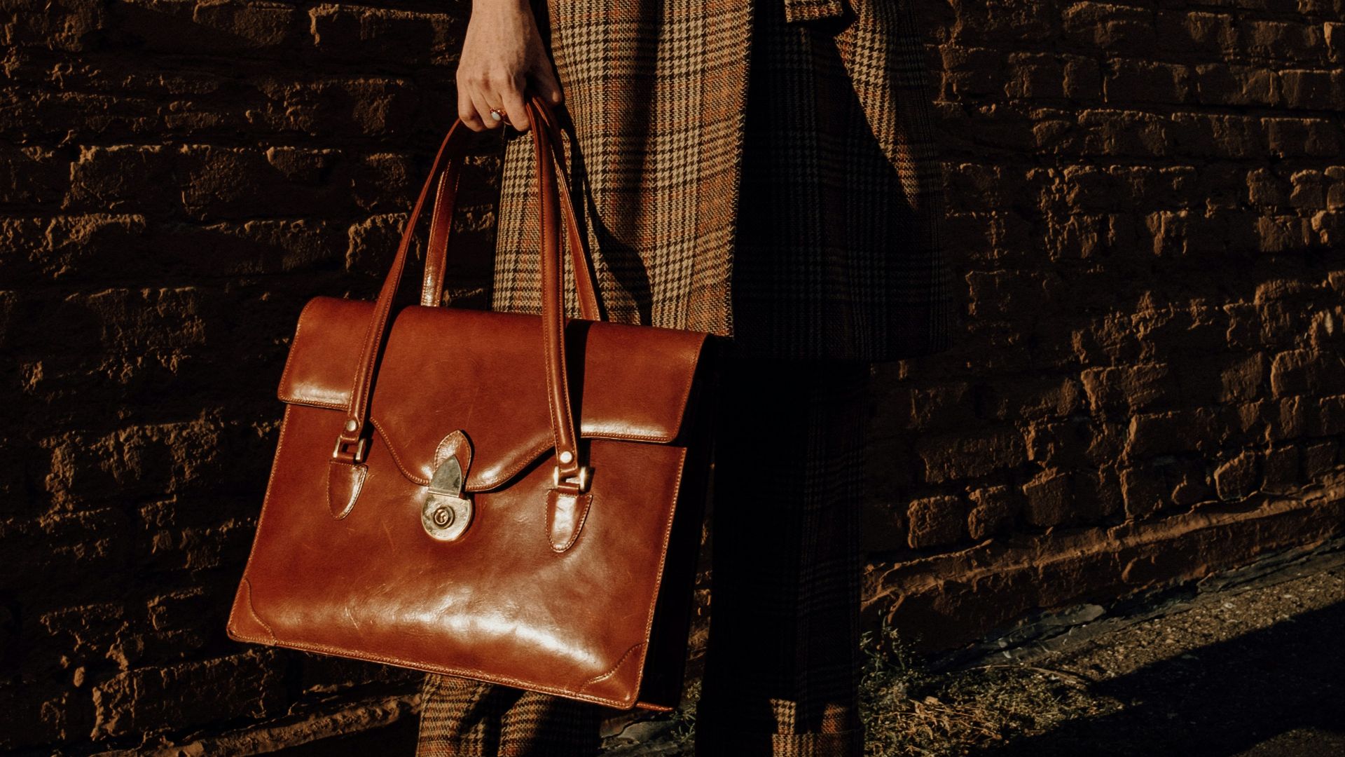 woman in brown coat holding brown leather handbag