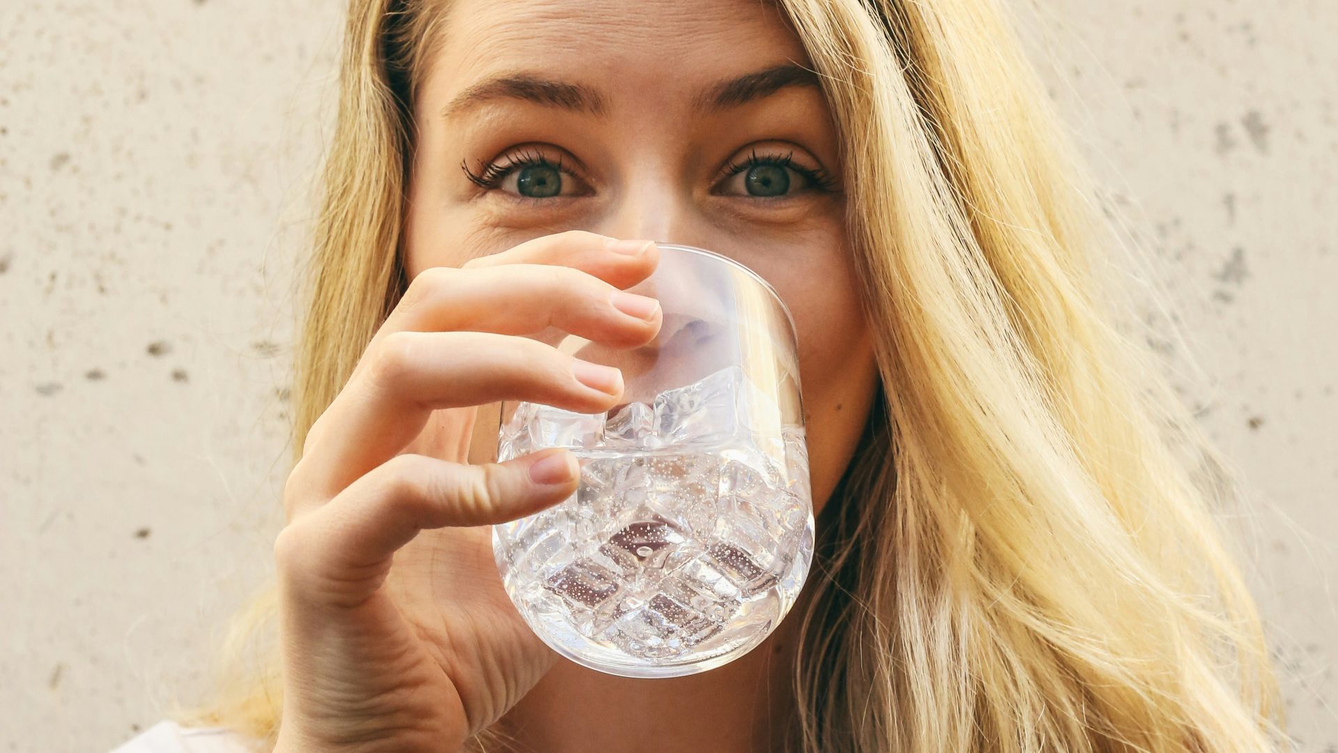 woman in white crew neck shirt drinking water