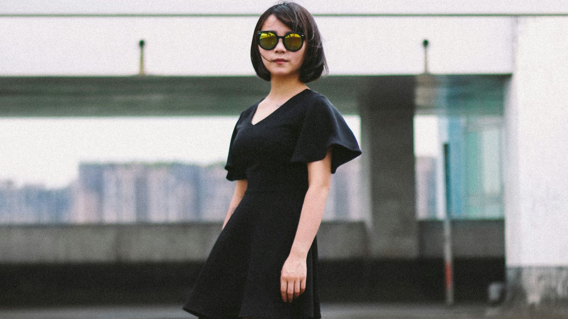 woman in black minidress and black sunglasses standing on street
