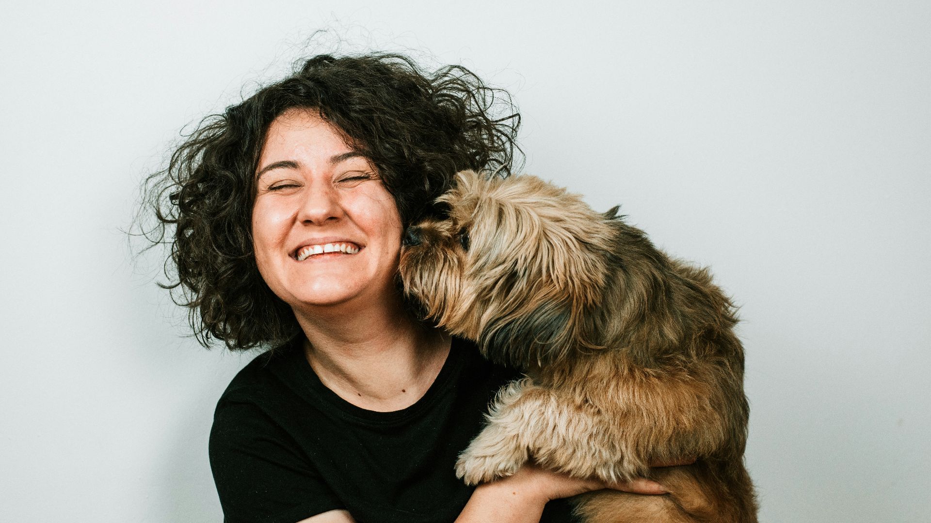dog kissing woman in black crew-neck shirt