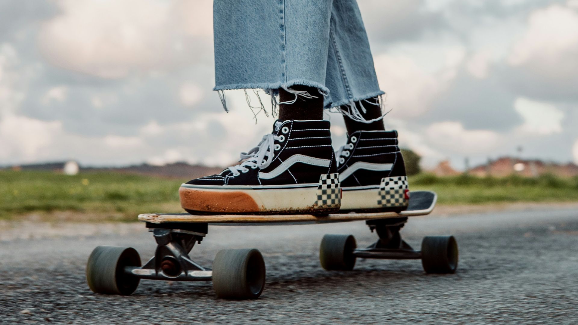 person in blue denim jeans and brown leather boots holding black and white bottle