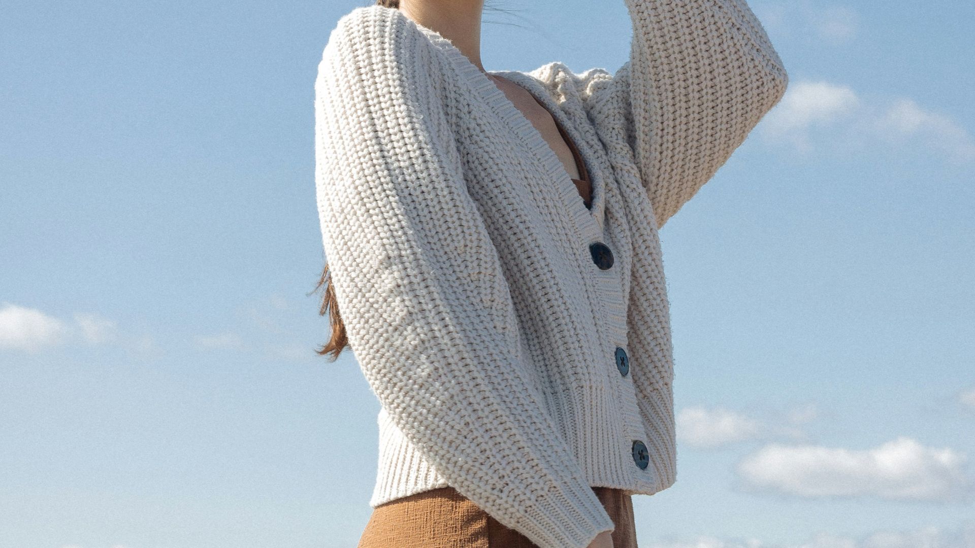 woman in white knit sweater and brown shorts standing under blue sky during daytime