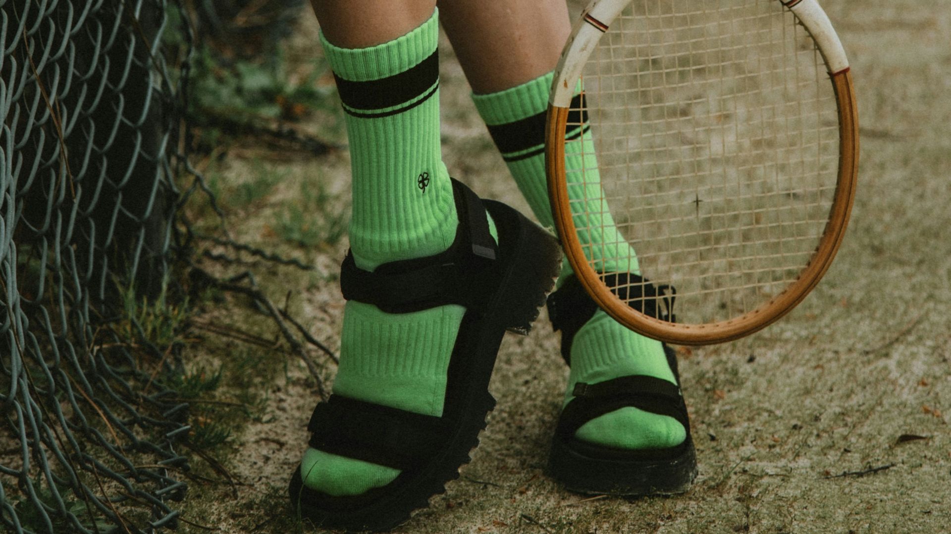 woman in white skirt and green socks holding brown and white tennis racket