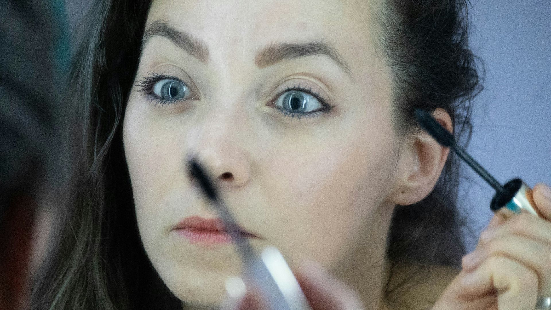 a woman is doing makeup on her face